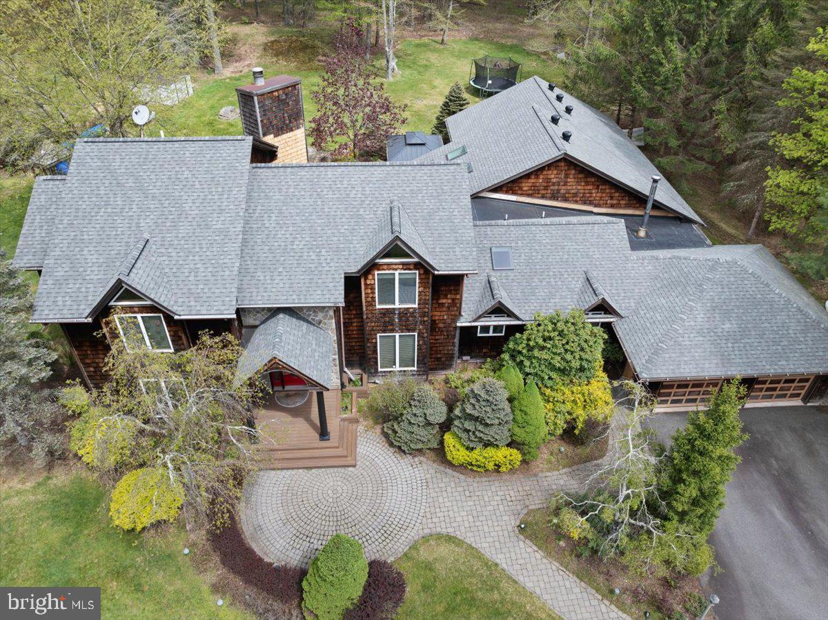 Welcome to this extraordinary contemporary retreat in the heart of the Poconos, where one of the home’s most unforgettable features sets the tone from the moment you arrive a spectacular PRIVATE INDOOR POOL  designed for all-season enjoyment, entertaining, wellness, and relaxation unlike anything typically found in the area.
Set on over two beautifully manicured acres within a private lake community featuring access to a peaceful electric-only lake, this fully TURNKEY residence offers 4,000 square feet of thoughtfully renovated living space blending modern comfort with warm mountain-lodge character.
From soaring 14+foot ceilings and expansive entertaining spaces to a dedicated home gym and newly renovated interiors throughout, every aspect of this home has been designed to create an elevated retreat experience. Whether hosting unforgettable weekends, enjoying cozy winter escapes, or embracing full-time resort-style living, this property delivers a lifestyle that feels worlds away from the ordinary.
The completely renovated kitchen serves as the heart of the home and features wraparound quartz countertops, a large center island with quartz surfaces, custom cabinetry, induction cooktop, stainless steel appliances, updated backsplash, open shelving, pantry barn doors, and modern fixtures curated for both everyday living and entertaining.
The dramatic main living area welcomes you with soaring ceilings, updated flooring, statement lighting, and an inviting atmosphere that perfectly complements the surrounding natural setting. Updated patio screen doors create seamless indoor-outdoor flow to the newly constructed outdoor wood deck and exceptionally landscaped grounds.
Every bathroom throughout the residence has been extensively renovated with modern finishes including updated cabinetry, quartz countertops, refreshed tile work, upgraded plumbing fixtures, glass shower enclosures, designer mirrors, and spa-inspired details. The spacious primary suite offers a beautifully renovated bath retreat complete with soaking tub, double vanities, vanity area, updated flooring, and custom barn-door closet access.
Additional highlights include a dedicated gym with custom mirrors and updated finishes, oversized 2-car garage, beautifully maintained grounds, and extensive recent upgrades that make this property truly move-in ready.
Major improvements include a new roof, dual HVAC systems including one brand-new system and a second system less than three years old, updated pool heating system, updated pool filtration system, new pool cover, newer appliances, updated lighting, and extensive cosmetic and mechanical renovations completed throughout recent years.
Located within a peaceful private lake community with access to kayaking, paddle-boarding, and quiet days on the electric-only lake, this exceptional property offers the perfect balance of privacy, recreation, luxury, and year-round mountain living.
A rare opportunity to own a fully renovated turnkey Pocono retreat where resort-style amenities, modern upgrades, and unforgettable entertaining spaces come together in one extraordinary offering.