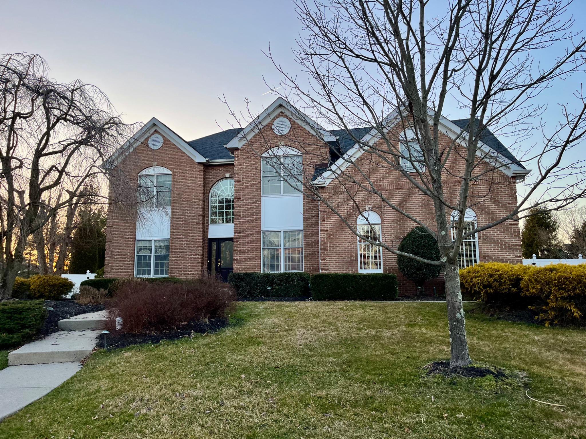 Welcome to this impressive 4-bedroom, 2.5-bath Colonial, distinguished by its stately brick façade, striking rooflines, and dramatic arched windows. Set amid mature landscaping, this Yardley residence blends timeless elegance with thoughtfully designed living spaces and a private backyard retreat. Step into the dramatic two-story foyer, where a sweeping staircase, rich Brazilian walnut hardwood floors, and abundant natural light set the tone for elegant spaces beyond. Double doors open to a private home office, while the formal living and dining rooms flow seamlessly together, showcasing architectural columns, wainscoting, crown molding, and a sun-filled bay window.The spacious eat-in kitchen is beautifully appointed with 42-inch custom cabinetry, granite countertops, a center island with a gas cooktop, and a wall of windows overlooking the pool and backyard. Open to the kitchen, the impressive family room features soaring cathedral ceilings, a stone-front wood-burning fireplace, and a dramatic second staircase rising to an open upper-level balcony, a striking architectural focal point that also provides convenient secondary access upstairs. A powder room and dedicated laundry/mudroom complete the main level. Upstairs, the spacious primary suite offers double-door entry, a sitting area, separate dressing vanity, generous walk-in closet, and an en-suite bath. Three additional generously sized bedrooms share a well-appointed hall bath. The basement provides flexible space for a recreation room, home gym, media room, or additional storage. Designed for year-round enjoyment, the private backyard features a spacious deck overlooking the heated in-ground gunite pool, along with two distinct patio areas offering plenty of space for outdoor dining, lounging, and entertaining. A fenced yard completes this inviting and secluded outdoor retreat. Ideally located in the highly desirable Yardley area within the Pennsbury School District, this home offers excellent commuter access to I-95, I-295, Route 1, and the nearby SEPTA train station.