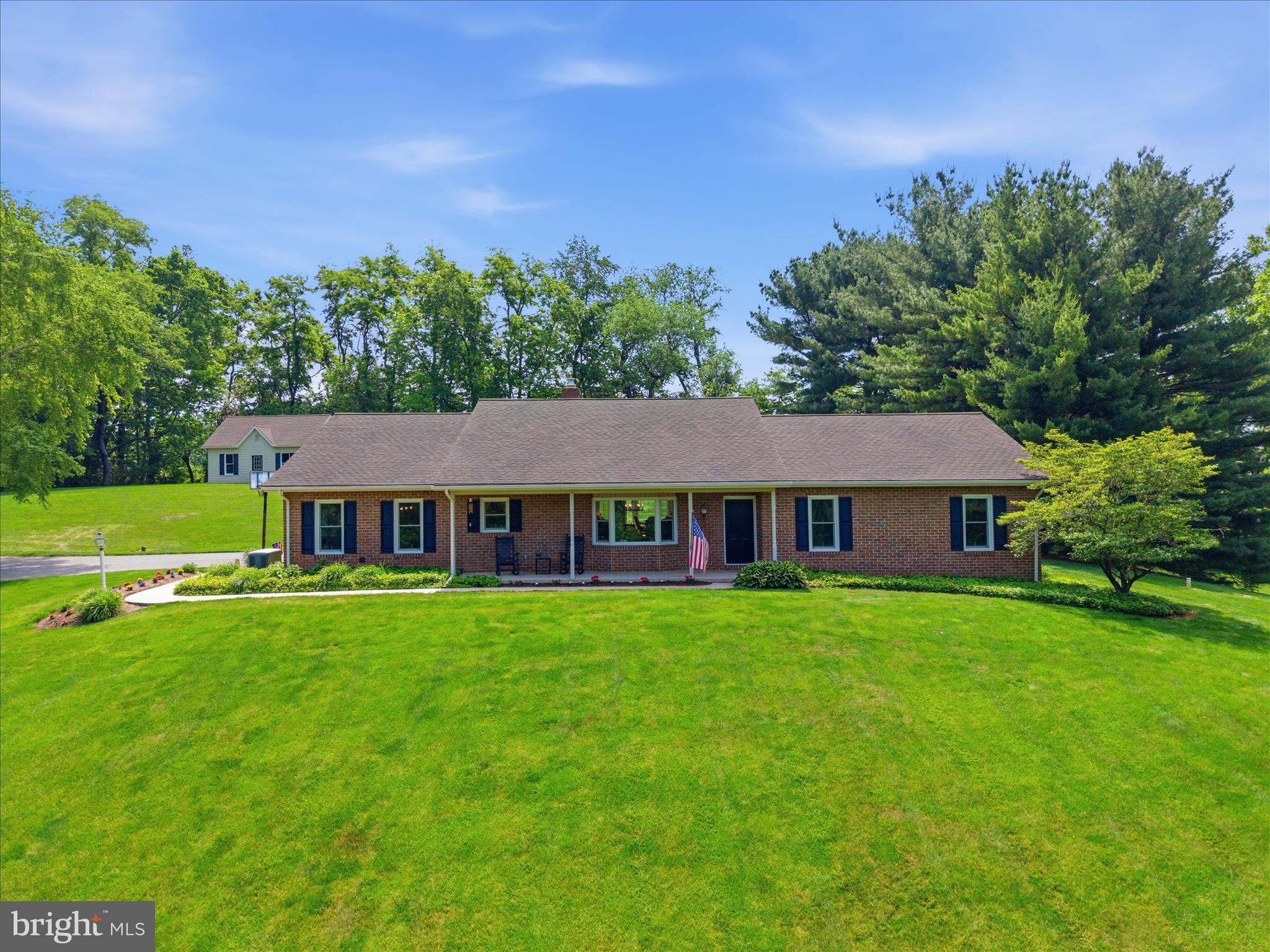Welcome home to this lovingly maintained brick rancher, custom built in 1987 by its original owners, who have cherished this property for nearly four decades. Nestled on 5.4 picturesque acres and surrounded by beautiful preserved farmland, this serene country retreat offers the perfect blend of privacy, comfort, and breathtaking Lancaster County views.
A broad front porch welcomes you inside, where hardwood floors flow throughout the entirety of the home. The heart of the home is the open-concept living room, dining room, and sunroom areas, designed for both everyday living and effortless entertaining. The living room features a stunning brick fireplace with mantel, built-in cabinetry, and a vaulted ceiling that adds warmth, light, and character to the space.
The sunroom is a true highlight, surrounded by windows that frame sweeping views of the lush backyard, stamped concrete patio, and rolling farmland beyond. The dining room offers a charming bay window, elegant lighting, and seamless access to the kitchen. The expansive kitchen is ready for gatherings of any size, featuring granite countertops, a huge brand-new cherry island, a large built-in pantry, and a discrete and convenient located laundry area. 
Moving back the hall to the bedroom area. The spacious primary suite serves as a peaceful retreat, complete with French doors leading directly to the backyard patio. A walk-in closet and a private ensuite bathroom complete the space. Two additional bedrooms are bright and airy, including one with a built-in solid cherry Murphy bed, making it easy to transition between a home office and guest room. A full second bathroom with an accessible curbless shower provides comfort and practicality for guests and family alike.
Downstairs to the basement, you'll find a large family room with plush carpeting, offering additional living and recreation space, along with two generously sized storage areas. Outside, the beauty of the property continues. Mature trees create a park-like setting, while nearby creeks and sledding hills add to the charm and enjoyment of country living. There is ample open space for gardening, recreation, or even the addition of a future pool. Car enthusiasts, hobbyists, and those needing extra storage will appreciate both the attached two-car garage and the detached two-car garage with additional storage space above and concrete pad for parking a trailer or RV.
This home is also zoned agricultural. Surrounded by preserved farmland and offering room to roam, relax, and create lasting memories, this one-of-a-kind property combines timeless craftsmanship, peaceful surroundings, and the rare opportunity to enjoy Lancaster County living at its finest.
Additional updates to the property include: 40-year roof (2000), new spouting and gutters (2021), installed geothermal heat pump, humidifier, and air filtration system (2025), new water heater (2022), new/refinished flooring (2022), new exterior windows (2022).