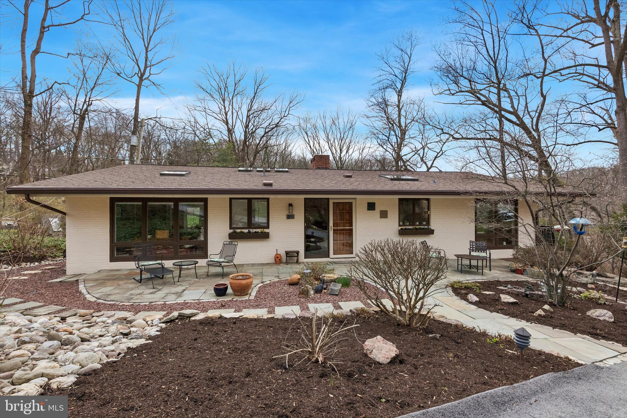 Set on a private lot, in a quiet cul-de-sac, yet in the heart of booming Wayne, 610 Arlyn Circle is an extraordinary contemporary residence designed and built in 1958 by legendary builder Robert McElroy. With its wooded backdrop and rare privacy, the property embodies the qualities McElroy championed throughout his career: architecture that grows from its landscape and invites daily life to flow in rhythm with nature. 
McElroy, a true pioneer of contemporary design from the late 1950s through the 1970s, crafted homes along the Main Line known for their dynamic rooflines, expansive floor-to-ceiling glass walls that invite sunlight and views, vaulted ceilings, and exposed beams—all optimized for hillside privacy and harmony with the land. 610 Arlyn is no exception. There is a reason the same owners occupied the property for 53 years! The home has been lovingly maintained and meticulously cared for throughout the years and it truly blends timeless design with comfortable everyday living.
The main level features a bright and airy living room, with a wood burning fireplace and overlooking a serene nature of the backyard; a welcoming and spacious dining area, and a kitchen with ample wood cabinetry and workspace—perfect for both daily living and entertaining. Generously sized 3 bedrooms and 2 well-appointed full baths provide comfort and functionality throughout the home and are located on the same level. An additional 4th bedroom and a full bath are located on the lower level next to a cozy family room with a wood burning fireplace, also overlooking tranquil views of the backyard. Ideally located in a highly desirable Main Line neighborhood, and in one of the best school districts in the entire country - Tredyffrin/Easttown SD! For food shopping, within 1-2 miles are the Wayne Farmers Market, Trader Joe’s, Whole Foods, Wegmans, or ACME. Less than a mile away is the Strafford station on the Paoli/Thorndale SEPTA regional rail line. Every imaginable retail store that you can think of is less than 3 miles away at the various locations in King of Prussia. All of the independent and boutique retail stores and restaurants along Lancaster Avenue in Wayne are just a 5 minute drive as is access to the PA Turnpike, Route 202 & I-76 for commuting in any direction. Within 2 miles there are also the Chester Valley and Radnor rail trails. Valley Forge National Historical Park is less than 10 min drive away. Superb location, yet tucked away in your own wooded oasis, come explore this Mid-Century Modern gem at 610 Arlyn Circle!