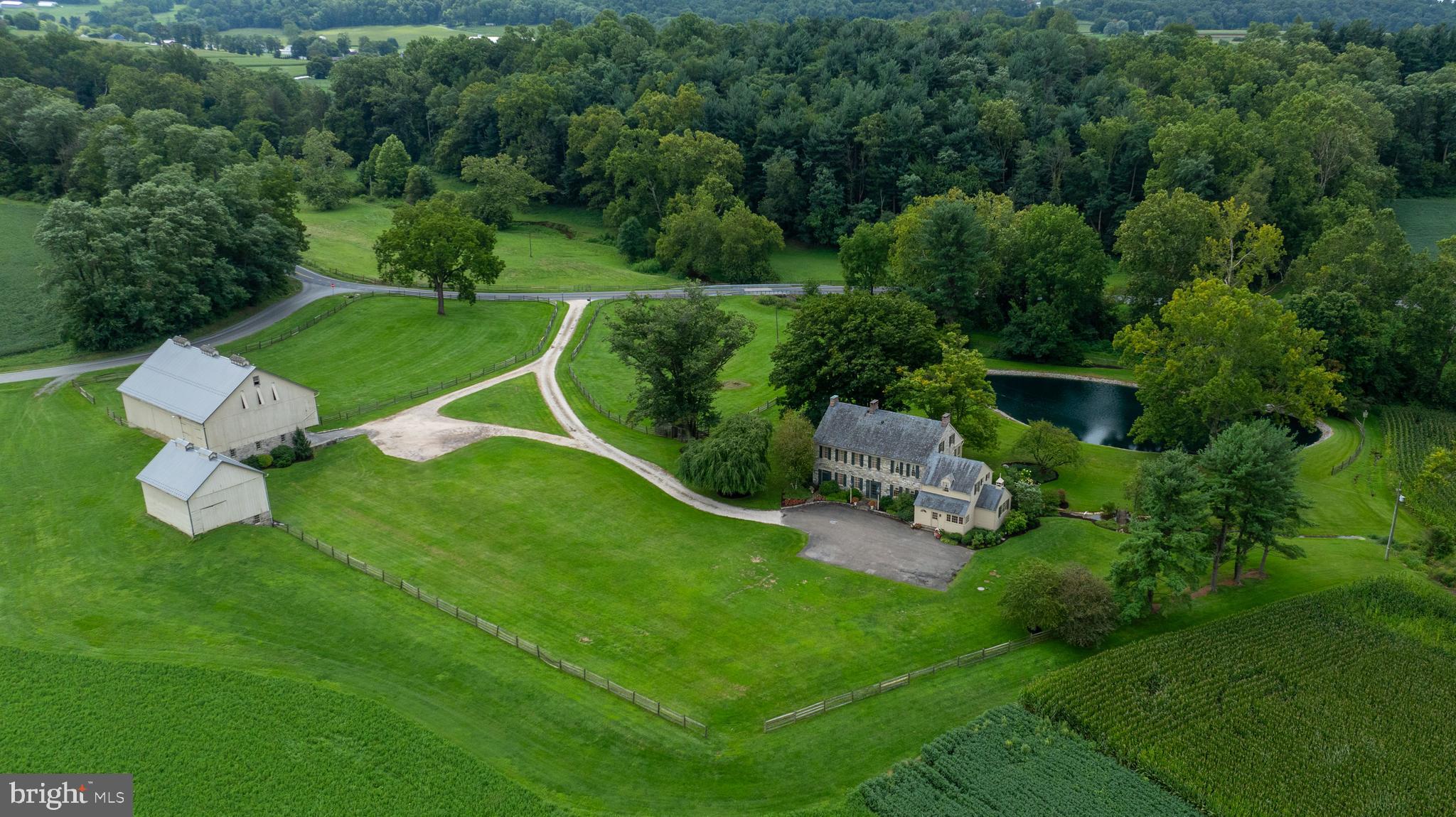 Welcome to Beaver Run Farm, a stunning 57.3+/- acre estate nestled in the scenic countryside of Strasburg, the heart of Lancaster County, PA.  This exceptional property offers a blend of tillable fields, wooded areas, fenced meadow / pasture, a meandering creek, pond and peaceful setting all surrounding a very special 2 ½ story stone home built in 1814, 51x76 Bank Barn and 30x36 Tobacco Barn.  The impressive 5,660+/- sq. ft. home features 7 Bedrooms, 4.5 Baths, 3 staircases, 4 fireplaces (non-working), deep windowsills, and historic charm and character that words simply cannot describe.  Extensive millwork & wood moldings, built-in’s, wide plank wood floors, and 9’6”+ ceilings are in many rooms throughout.  The home overlooks a picturesque pond, with multiple outdoor living spaces that are perfect for entertaining, including a covered porch, screened in porch, and patio, all with stone floors. The long driveway gently curves offering a tranquil approach to the private setting of the home.  At the front door you will be gracefully welcomed by a semi-circle stone step flanked by large classic lantern style lamppost lights adding to the historic character of the home.  Upon stepping in you will feel right at home with the warm glow of the wide plank wood floors in the centrally located grand foyer with curved staircase.  The Living Room boasts incredible millwork including sections of raised panel wood walls, heavy crown molding, chair rail, corner cupboard, fireplace with mantel, staircase to the 2nd and 3rd floors, and a hidden entry in the wall that can be opened to the Family Rm that creates a memorable space for entertaining.  The Family Room is highlighted by beautiful trim work, crown molding, built-in bookshelves, and fireplace with mantel.  The 21x15 Dining Room is truly unforgettable, with a LARGE fireplace, stone floor, raised panel wood wall, arched doorways, built-ins for dinnerware storage, and doorways leading to the screened in porch.  The expansive Kitchen with triple windows at the sink overlooking the pond and landscaped grounds, additional prep area with sink, plentiful cabinetry and storage space, breakfast nook with farmland views, large laundry area with cabinetry and sink, staircase to Primary Bedroom Suite area and bedroom that could be an ideal office.  The enclosed Porch/Mudroom is just off the kitchen with outside entrance for “everyday” use to driveway.  The Primary Bedroom Suite features a fireplace, crown molding and chair rail, closet area, primary bath with tile floor, water closet, two sinks and a walk in tile shower. The additional four bedrooms and two full baths on 2nd floor each have their own charm and character.  Two more bedrooms and full bath on the third floor each with cathedral ceilings and exposed wood beams, and one of the bedrooms having a built in desk, shelves, drawers, and storage space. The lower level of bank barn contains the garage that is deep enough for two cars.  The First Floor of the home has Central Air Conditioning.  The Property is enrolled in Act 319 (Clean & Green) and is Zoned Agricultural.  The Property is located on both sides of the road – see GIS view of parcel.  Location offers a rural country setting while being closed to major cities and airports.  It’s approximately 1.5 hours from Philadelphia and Baltimore, 2.5 hours to Washington, DC, and roughly a 2 ¾ to 3 hour drive to New York City.  This may be a once in a lifetime opportunity to acquire this rare property!