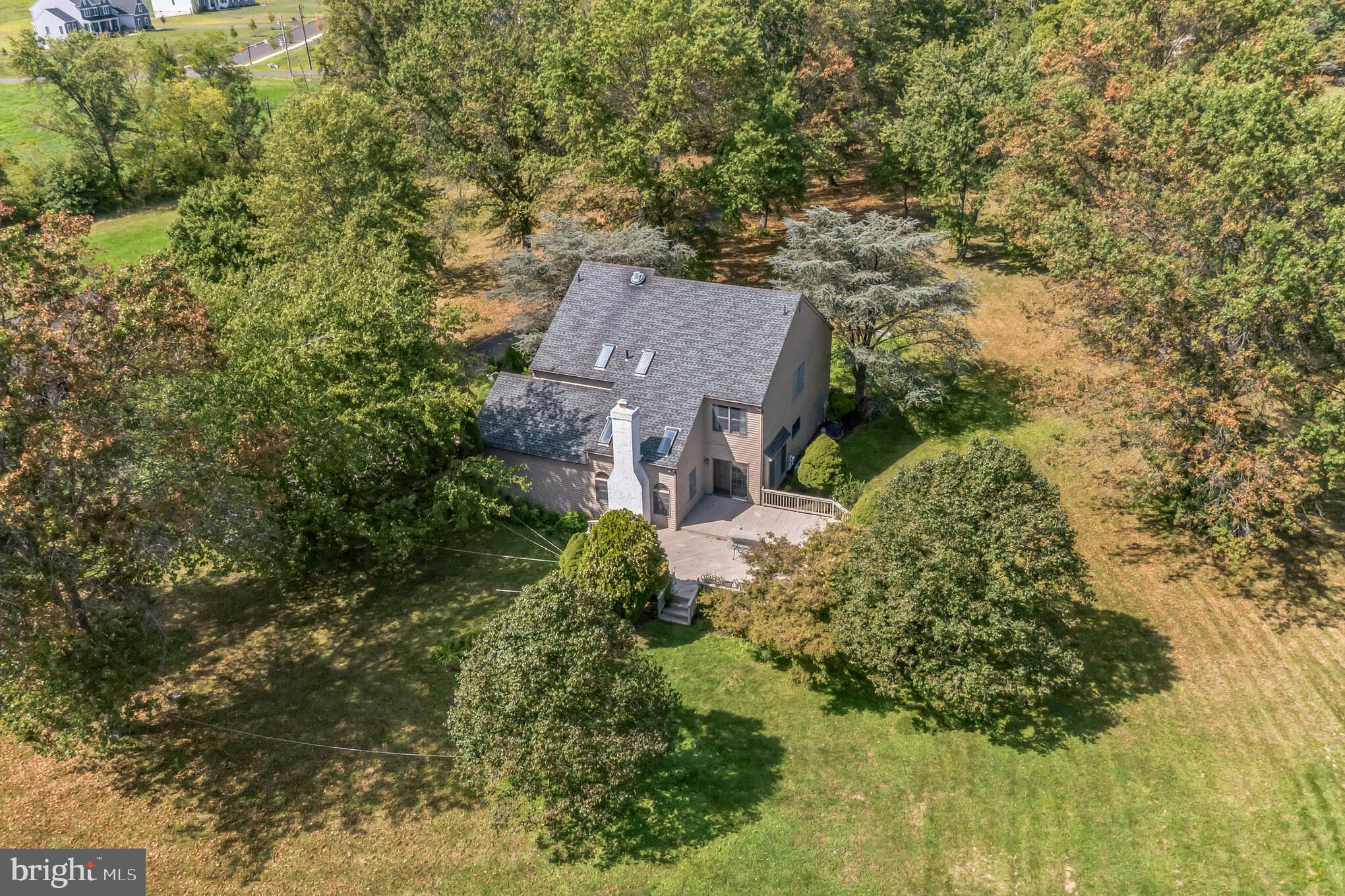 Down a long driveway, in beautiful New Britain Township, sits a custom built 4 bedroom 2 ½ bath colonial home on one of the most desirable lots in Bucks County.  Turn down the tree lined driveway and on either side, you will see expansive open fields.  Entering the home, you are greeted by a large foyer with high ceilings and beautiful hardwood floors throughout the first floor.  To your right is a sizeable sunken living area with tons of natural light, and to your left is the formal dining room leading you to an eat in kitchen with island cook top and lots of storage space.  A convenient first floor layout, the light filled family room, with wood burning fireplace and stone hearth, is right next to a large laundry/mudroom with access to the outside, as well as the oversized attached garage.  Sliding doors from the family room lead to a big deck overlooking the absolute essence of this home, which is the nearly 14 acres of land on which the house is situated.  Open and beautiful tree lined pastures as far as the eye can see, will transport you back in time when, yes, there was land to live on!  Perfect for anyone who loves animals, a chicken coop is already on the property, next to a detached 3 car garage and a vegetable garden.   Back inside there is a lot more to explore. The second floor offers a master suite with a large closet and linen closet, a dressing area and a large ensuite with jetted tub and stall shower.  Three very large bedrooms share a tiled hall bath with a tub-shower combo.  The large basement is partially finished and is equipped with a FULL kitchen complete with gas(propane) cooking and tons of counter and cabinet space as well as a large additional unfinished storage space in the back!  Located in the highly acclaimed Central Bucks School District, and minutes from both Peace Valley Park as well as the quaint Borough of Chalfont, how could you go wrong?  This is a truly one-of a kind home and has been lived in and loved for many years.  Come tour this unique property and begin making new memories here to last your lifetime!