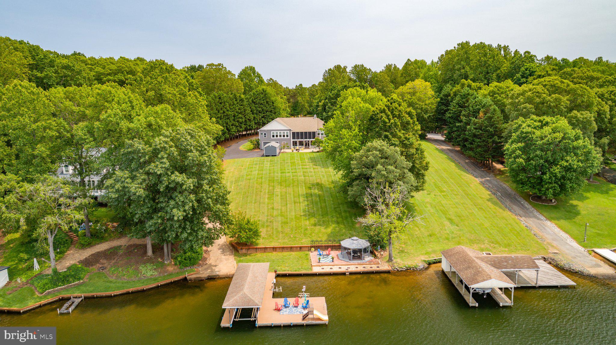 PRICE IMPROVED!!! INVESTORS-- NEW KALAHARI RESORT SPORT & CONVENTIONS IS JUST UNDER 40 MINUTES FROM THIS PROPERTY AND ON PRIVATE SIDE  OF LAKE ANNA! ONE OF KIND CUSTOM LAKE ANNA WATERFRONT HOME-NO HOA!  OVERSIZED 4 CAR GARAGES & LONG DRIVEWAY TO PARK EXTRA VEHICLES. ITS A BOATING ENTHUSIAST’S DREAM HOME W/SUNSET VIEWS!! Whether you have been looking for an incredible investment opportunity or your own personal sanctuary, you need to see this one of a kind 5BR, 3BA home which has approx. 4700 sq.ft. of finished living space. Enter this private, serene 2.65 acre oasis through the brick entrance columns. Enjoy your morning coffee on the covered front porch while taking in nature and the soothing lady fountain. As soon as you enter this meticulously maintained home, you will feel life's stresses melt away. This is the perfect place for large gatherings that still provide many areas for intimate conversation. From the elegant formal dining area to the living room with elevated tray ceiling, gas fireplace with mantle and custom cabinetry to the sunroom or to the massive 3 season room living area you will find a special place to enjoy the lake. Beautiful plantation shutters accent the elegant space. High ceilings and beautiful low maintenance Luxury Vinyl plank flooring throughout the home. Continue into the large gourmet kitchen with island, double ovens, induction cooktop, dishwasher, French door refrigerator, built-in microwave, walk-in pantry and access to garage through laundry room. Stainless appliances. Expansive granite counter space and abundant custom cabinetry. Serve meals in the formal dining area, at the counter, or in the additional generous dining area off the kitchen. Parties easily flow into the 3 season room with fans, generous space for eating or lounging while taking in the breathtaking view of the private side of Lake Anna. Maintain privacy with a split bedroom design. Large main level ensuite primary bedroom is a sanctuary with its wall of windows overlooking your private backyard and gorgeous water views. Huge walk-in closet even has its own closet for shoes, bags or other items. Primary bathroom has two separate vanities, each with generous counter space. Large tiled shower with seating, dual shower heads (rain shower & hand held). Generous custom cabinetry has space for your linens and other personal items. Separate sunroom area with magnificent views could be used as an office, bedroom, music room or a place to just hang out. Two additional bedrooms, a bathroom with tiled tub/shower and a linen closet complete the main level. The walk-out lower level with approx. 2000 sq.ft. of additional finished space has two additional bedrooms, full bath with tiled shower/tub, a large family room/entertainment area is ready for your guests. Abundant additional storage space. Walk out to the huge covered patio with hot tub, porch swing, and sauna (as-is) overlooking the lake. Looking for garage space?  You found it!  Oversized 2 car garage on main level. Continue down to the asphalt drive way to another oversized 2 car garage deep enough for your boats. Large 12’x21’ multipurpose shed with, windows, built-in shelving, garage door for another parking space, storage or space for crafter or hobbyist. Walk or drive down the asphalt driveway to your own concrete boat ramp. Incredible level waterfront entertaining area with gazebo on concrete, and large freshly painted patio. Could be excellent for small weddings and other entertaining. Your private deep water boat house (10.5’depth) awaits.  Complete with storage area, large sun deck, electric lift, water slide and two PWC lifts. Short boat ride to dike 2 to enjoy 4th of July fireworks.  This property would be an incredible investment opportunity with potential for 2 separate rental levels and NO  HOA!  10 minutes to Food Lion, ABC,  shopping, restaurants and veterinarian. Co-listing agent is property owner. DON'T WAIT!  YOU CAN ENJOY THIS HOME TO CELEBRATE LABOR DAY!