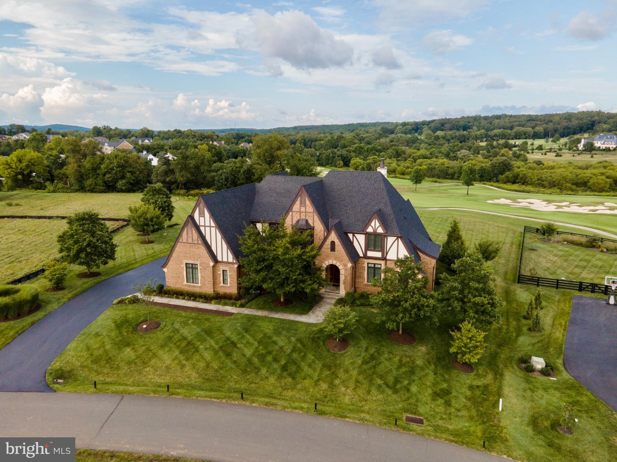 **Offering $50,000 toward a Creighton Farms Golf Club Membership with acceptable offer** Nestled behind the gates of the sought after Creighton Farms Country Club community, this magnificent masterpiece built by Visnic Custom Homes sits on 1.14 pristine acres and overlooks holes 1,8, 16, and 18 of the premier Jack Nicklaus Signature Golf Course. This English style Tudor combines an elevated modern elegance with Old World architecture and boasts sophisticated details and design elements around each and every turn including hand-scraped hickory hardwood floors throughout the main and upper levels; elegant crown moldings; graceful archways; two-story, 30' cathedral, beamed ceilings in the heart-of-the-home - the Kitchen and Great Room; Gourmet Chef's Kitchen with 8.5' entertaining island with granite counters, soft close cherry cabinetry, commercial grade Thermador appliances that include a separate refrigerator and freezer, two dishwashers, build in microwave, six-burner + griddle gas range and double ovens (one of which is convection); Butler's pantry with sink and beverage station connects the Kitchen to the formal Dining Room; Great Room with a cozy, stone, gas fireplace, backlit Scottish Knot above mantle, and double French doors that allow your living and entertaining spaces to seamlessly flow to the outdoor, covered, bluestone Terrace with ceiling fans, gas line for grille hookup, a brick wood burning fireplace, and picturesque golf course and mountain views for as far as the eye can see; Primary, main-level Bedroom boasts vaulted ceilings, breathtaking mountain views from the Sitting Nook, an incredible walk-in closet and dressing area, En Suite Spa Bath with marble floors, jetted tub, walk-in glass shower, dual sink vanity and private water closet; light filled Home Office could also serve as an additional Guest Bedroom that would be serviced by the full hall Bath; charming spiral staircase will guide you to the Juliette Balcony on the upper level; the upper level also hosts three additional Bedrooms, each with their private En Suite Bath and walk-in closet; Bedroom 1 on the upper level provides access to the Eagle's Nest, which could serve as a Sitting Room or a second Home Office;  the expansive lower level of the home boasts a huge Rec Room, a Poker Room with wet bar and Kitchenette, a Billiard Room the provides access to the lower level Terrace/Outdoor Cigar Lounge, a Fitness Room with a dry-sauna, a full Bathroom, and unfinished space that could be finished off into a golf simulation room; built-in indoor and outdoor speaker system; three-zone Geothermal heating and cooling (Primary Bedroom has its own zone); two water heaters; CAT-6 wiring throughout; an area where an elevator could be installed; 18-zone irrigation system runs off of community well (and not your public water); central vacuum; security system with two panels, motion detectors and shatter/window sensors and a three-car side-load garage with finished flooring and an abundance of storage area. Creighton Farms is one of greater Washington DC’s most extraordinary, exclusive private club communities. The crown jewel at Creighton Farms is the 18-hole Jack Nicklaus championship golf course. Unparalleled resort style amenities include a brand-new state of the art golf facility with heated indoor bays, two Har-Tru & two USTA hard-surface tennis courts, fitness & wellness facilities, a resort style pool and an elegant Club House offering indoor & al-fresco dining, overnight club rooms for members and guests, Board Room, Library, Golf Shop & more.