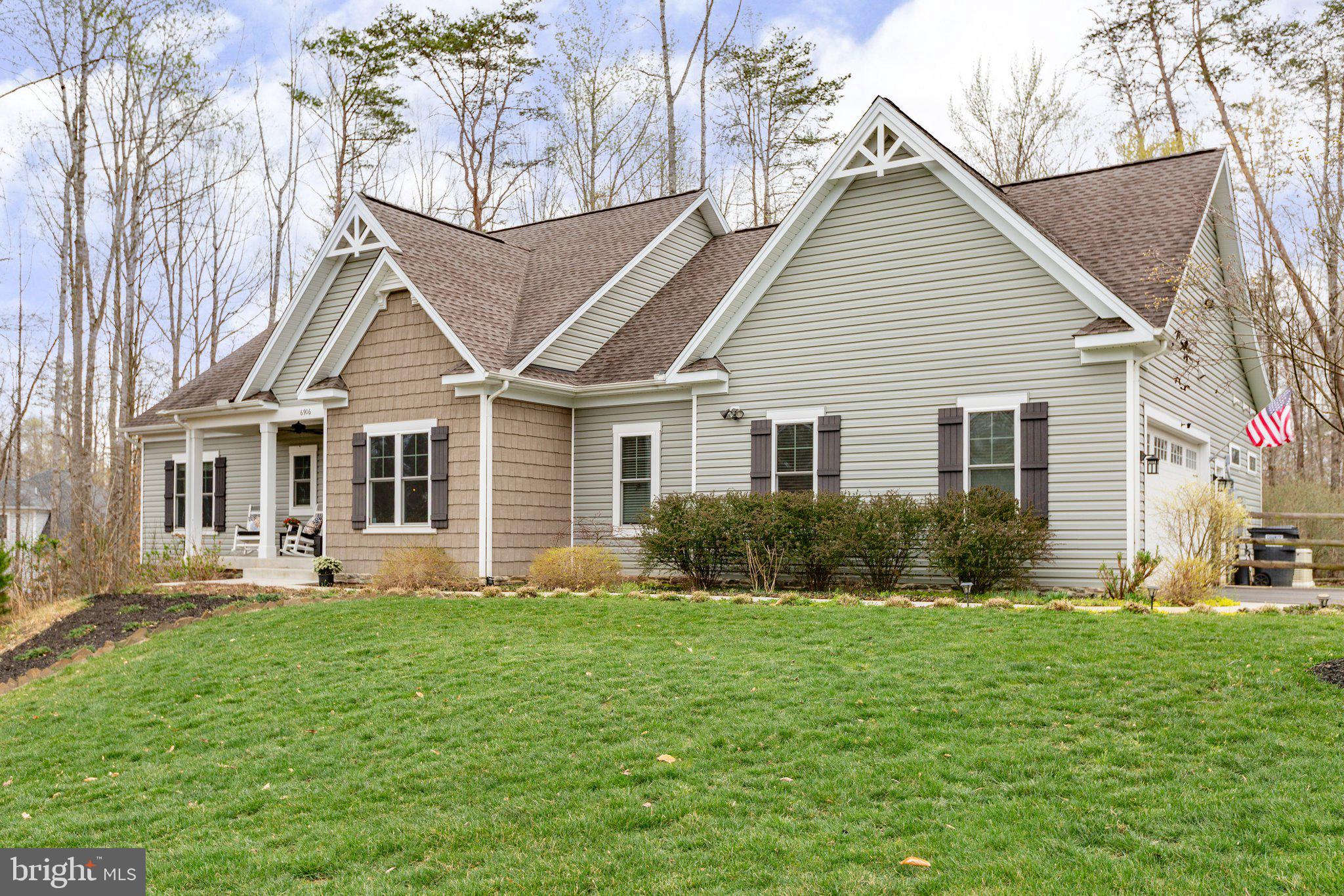 Park-like acreage, expansive single-level living and minutes from so much Fredericksburg region action? 6906 Barclay Drive is a must-see! Constructed in 2017 and showing like-new, this residence includes three bedrooms, 3.5 baths and almost 3,300 square feet of living space (including a recently updated
basement!). It sits on a roomy two-plus-acre lot in the River Glen community in Spotsylvania County. The community is lush with green spaces and has a low-fee HOA. Zooming in on the homesite, the home is nestled on a picturesque perch well off the road. A winding asphalt driveway and green lawn leads you to the residence – there is so much privacy here! For parking, there is a side-loading, two-car garage with ample shelving, work benches and pedestrian door. The broader landscape includes tasteful dots of willow, dogwood and magnolia trees. Out back, you’ll see a portion that’s fenced and ready for Fido. The undeniable anchor is its two-level deck, with a lower-level portion with a hot tub built-in – wow! For all of your lawn equipment there is a 12x12-foot shed. The home itself is a totally-customized Travilian Homes build exuding craftsman charm. Its exterior is a green-gray hue with dark shutters and several windows donning its frontside. Heading inside, it’s a stunning, open view as you’re greeted with an expansive foyer and white oak flooring that stretches throughout. There’s a flex space with a large closet, which may easily be an office or formal dining room. Continuing, the great room includes soaring cathedral ceilings and a granite-surrounded gas fireplace. The kitchen is draped in modern gray cabinetry, a gray-white tile backsplash, stainless steel appliances (note the modern hood!) and granite countertops. As for the bedrooms, it’s split floorplan bliss. The laundry room (tons of cabinetry!), a half bath and the primary suite are all on one side. The primary suite is stunning with two walk-in closets, French doors to the deck and an ensuite bath complete with a 7x3-foot Roman shower, dual sinks, granite countertops and beige tiling. The two secondary bedrooms are carpeted with large closets. Between these two bedrooms you’ll find a full bath with an extra-deep tub/shower combo. Heading to the basement, it has brand new carpet! Highlights include a large, carpeted flex room; a fully-tiled bathroom with a walk-in shower; a 15x16-foot workshop with three 20-amp circuits; and more than 600 square feet of unfinished storage space with utility sink. For bonus storage space, there is a conditioned crawl space. Systems-wise, the HVAC and hot water heater have been regularly maintained and there is a generator. For as serene as the residence is, it’s also incredibly convenient! Within 15 minutes you can be to multiple shopping, dining and grocery destinations within Central Park and along Route 3. I-95 access (Route 3 exit) is also within 15 minutes and the heart of Downtown Fredericksburg is within 20 minutes east! For outdoor adventures, Motts Run Reservoir Recreation Area is within a five-minute drive. Prepare to check so many items off your wish-list – an open design, like-new living, convenience and more!