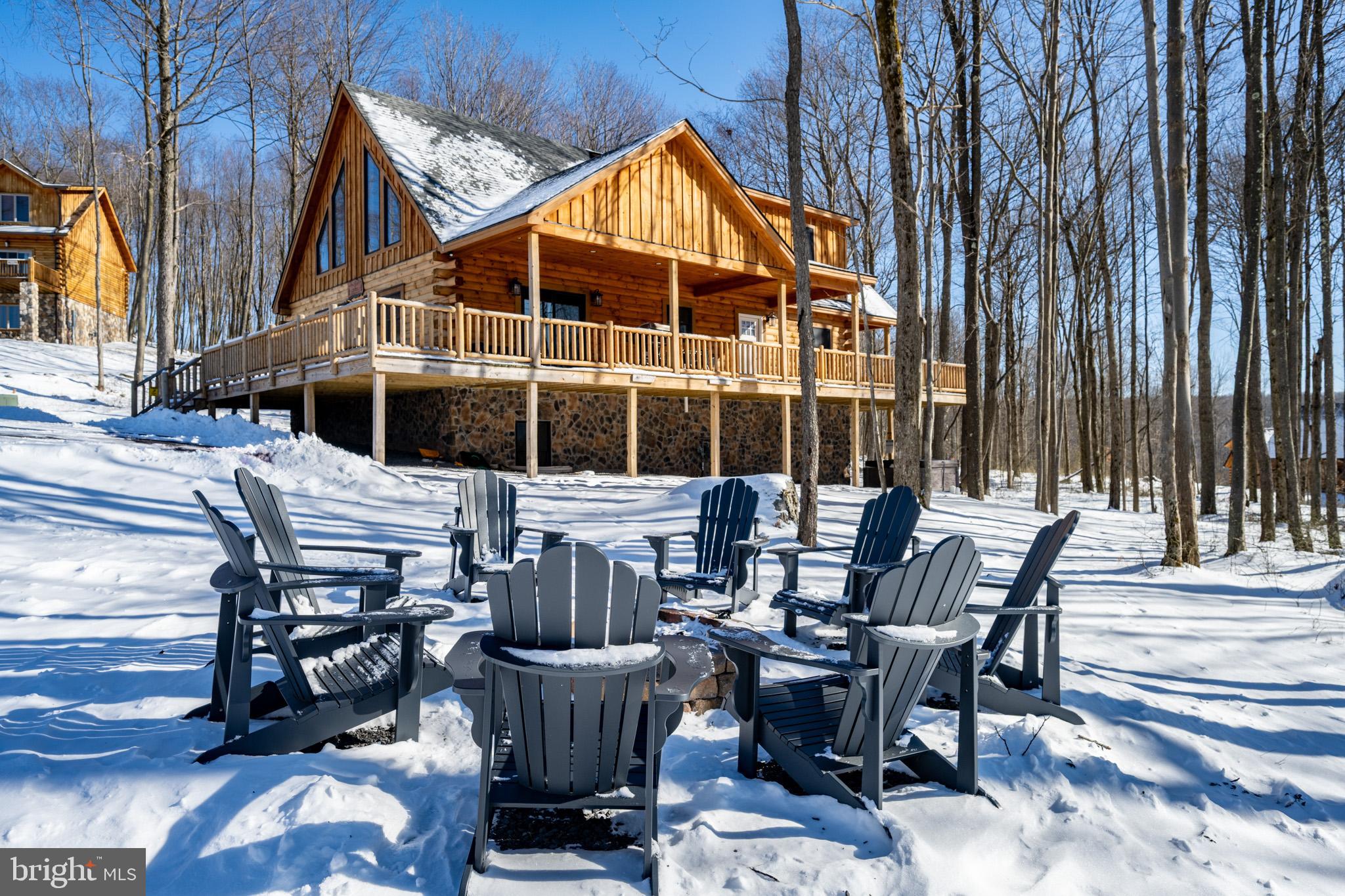 Private wooded setting in North Camp Ridge, just minutes from Wisp Resort, Fork Run, and Deep Creek Lake. This 5-bedroom, 5.5-bath log chalet offers three finished levels with an open-concept main floor and an oversized loft above. Rustic character meets modern finishes throughout, including a kitchen with stainless steel appliances, custom hardwood cabinets, granite countertops, and bar seating. A stacked stone fireplace anchors the main living space, with abundant glass pulling in natural light. The walk-out lower level adds a second living area and game room. Five en-suite bedrooms support flexible use as a vacation rental or private retreat. Outdoor features include a wrap-around deck, hot tub, and fire pit. A well-rounded mountain home with space, privacy, and close access to year-round amenities. Call today for details!