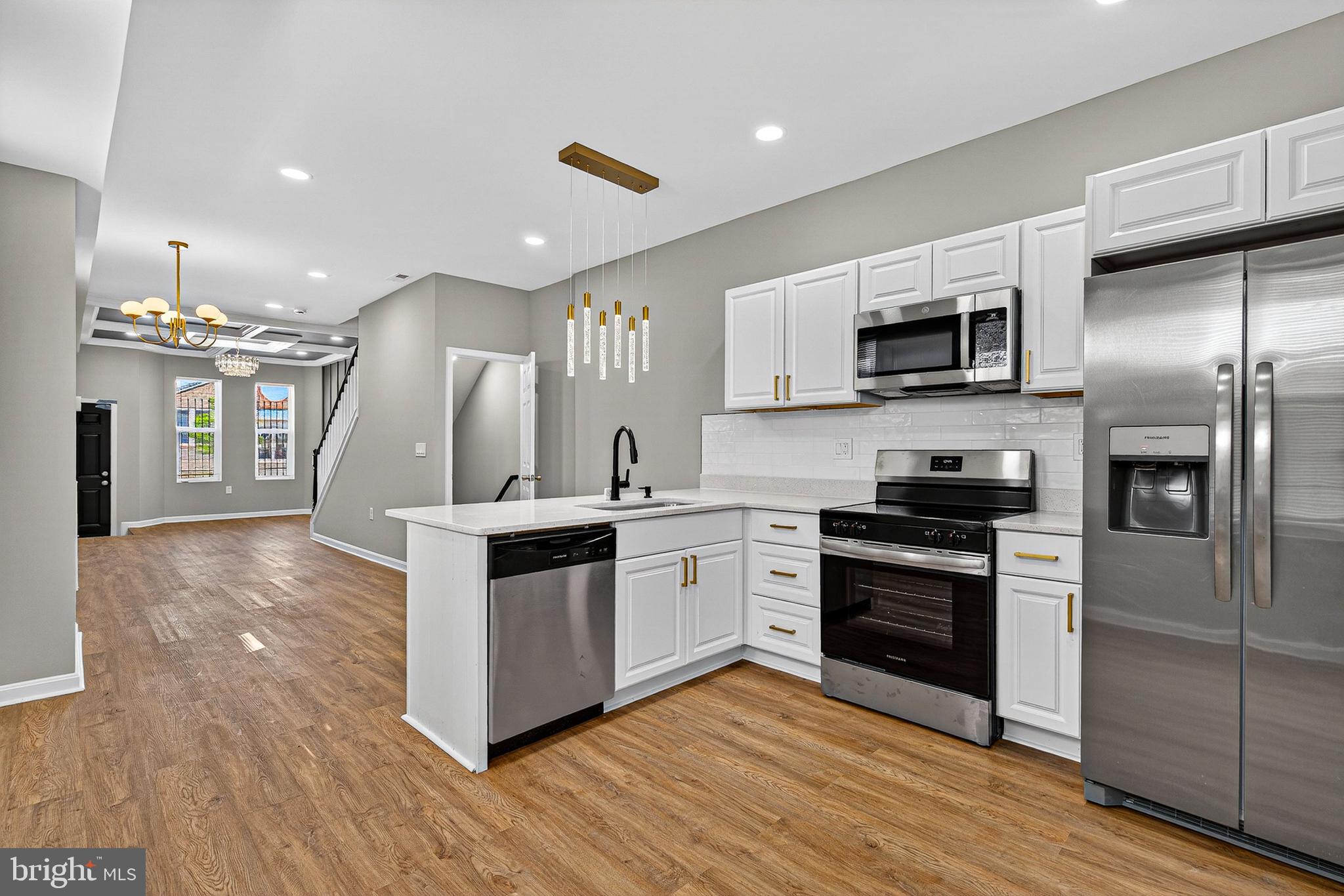 Welcome to this stunning, fully renovated end-unit rowhome that masterfully blends contemporary architectural flair with functional urban living. No detail has been overlooked in this top-to-bottom transformation, offering a sophisticated sanctuary in the heart of Baltimore.
Step inside to an expansive, light-filled open concept main floor featuring high-end luxury wide-plank flooring and recessed lighting throughout. The living area is a true showstopper, anchored by:
 A dramatic coffered ceiling with deep charcoal insets and a glittering crystal chandelier.
A floor-to-ceiling geometric slat accent wall that adds texture and modern dimension to the space.
A bright, airy layout that leads effortlessly from the living room into the dining area and chef’s kitchen.
The heart of the home is designed for both everyday living and high-end entertaining. Sparkling white quartz countertops paired with a classic subway tile backsplash.  A full suite of stainless steel Frigidaire appliances, including a gas range and a French-door refrigerator with a built-in water dispenser. Bright white shaker cabinets finished with elegant brushed gold hardware. An oversized breakfast bar with a deep under-mount sink and modern black gooseneck faucet, illuminated by striking pendant drop lighting. Generously sized rooms featuring neutral tones, ceiling fans, and ample natural light.
Experience designer luxury with custom tile work, including a walk-in shower with a rainfall head, niche shelving, and sleek matte black fixtures. The vanities feature quartz tops and contemporary LED-ready mirrors. Extra windows allow for an abundance of natural light compared to traditional rowhomes.
All-new HVAC, plumbing, and electrical for total peace of mind. A classic Baltimore brick facade with professional black trim accents and a secure, private rear entry.
Schedule your private tour today and experience one of the finest renovations 21217 has to offer!