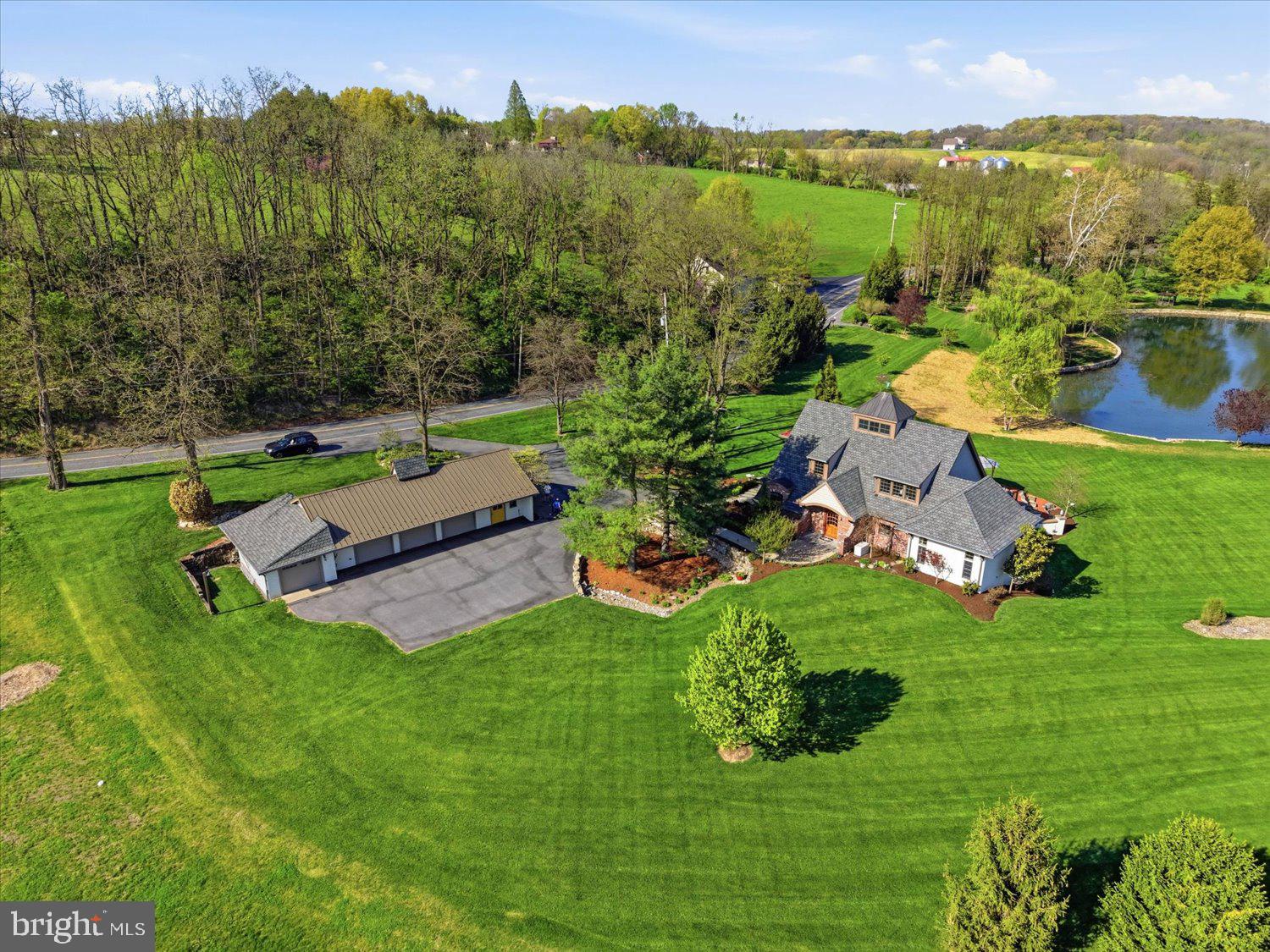 Set across two parcels totaling just about 12 acres, this extraordinary property offers a rare blend of privacy, natural beauty, and thoughtful design. The main parcel features a charming brick cottage-style home on 1.84 acres, while the adjoining 10.22-acre parcel provides potential for an additional residence. Enrolled in Clean and Green, the setting is tranquil, scenic, and rich with wildlife.  

Surrounded by lush gardens and mature landscape, the home welcomes you with a stone walkway and arched transom entry, creating a storybook first impression. Inside the home features custom architecture and thoughtful design finished with the assistance of Brownstone Design. Soaring ceilings, expansive windows, radiant heated floors, and French-imported hardwood floors are found throughout the home. 

The main living area features dramatic two-story ceilings filled with natural light from the walls of windows and hardwood floors- all seamlessly connecting the family room and kitchen. The kitchen is both functional and distinctive, highlighted by reclaimed wood beams from a family barn, curated marble countertops, pendant lighting, double sink, a built-in dining table, and premium appliances including Bosch refrigerator, KitchenAid oven, and JennAir stove top. 

Privately positioned on the main level, the primary suite offers a peaceful retreat with tray ceiling, carpeted floor, window treatments, and access to a private balcony overlooking the backyard and pond. The en-suite bath is beautifully appointed with designer finishes, wall sconces, recessed lighting, a spacious walk-in shower, and an expansive custom closet. A full guest bath on the main level features elegant details including marble accents, hex tile flooring, walk-in subway tile shower, and designer lighting. 

A sunroom just off the main living area provides a cozy yet bright space with a gas fireplace, plank wood ceiling, slate shelf built-in, and panoramic views of the surrounding landscape. A sliding barn door leads to the mudroom/laundry room, complete with custom cabinetry, wainscoting, Speed Queen washer and dryer, storage closet, and side entry access. 

Upstairs, a loft overlooks the main living space and captures stunning views of the property, enhanced by a dramatic cupola with windows. The upper level also includes access to a carpeted attic/crawl space for additional storage. 

The walk-out lower level is expansive and unfinished, offering concrete floors, utility access, and two sets of double doors to the exterior—providing excellent potential for future bedrooms, living space, or recreation areas. 

Outdoor living is truly exceptional, with a slate patio designed for entertaining, complete with retractable awnings, garden space, and peaceful views of the private pond. The pond is stocked and framed by stonework, offering opportunities for kayaking, fishing, or simply enjoying the serene setting. A gazebo, willow trees, and open green space further enhance the landscape. 

Additional features include a converted barn serving as a spacious 4-car garage and workshop with a half bath, ample storage, and multiple access points. With township-owned land bordering two sides, the property offers added privacy and long-term peace of mind. The additional 10.22-acre parcel presents a rare opportunity for future expansion, offering the potential to build a second residence—ideal for a private estate, guest home, or multi-generational living scenario. 

A truly one-of-a-kind retreat where craftsmanship, nature, and tranquility come together.