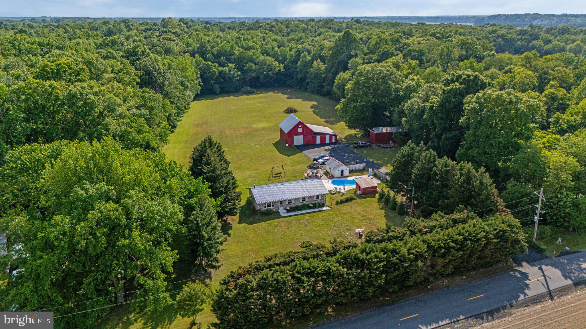 Welcome home to your own private 14.55-acre country oasis at 310 Dogtown Road, a place where peaceful homesteading and backyard resort living come together in perfect harmony. From the moment you arrive, you’ll love looking out across the street at the protected landbank farm, ensuring your panoramic field views remain untouched forever. Best of all, this expansive property comes with absolutely no restrictions or HOA regulations, giving you the ultimate freedom to truly live on your own terms. Whether you dream of raising livestock, expanding your homestead, parking your RV or boat, or building additional structures, this land is a blank canvas for your imagination. The heart of this estate is a warm and welcoming ranch home designed for easy living, offering four bedrooms and two bathrooms, including a highly convenient first-floor laundry room transformed from one of the bedrooms (complete with a brand-new washer and dryer!). Built with incredible flexibility and no interior load-bearing walls, this home invites you to easily bring your own open-concept vision to life. Every major update has already been lovingly taken care of for your total peace of mind, from the brand-new paved driveway and a two-year-old central A/C system to a durable four-year-old metal roof, a whole-house backup generator, and a brand-new refrigerator. Step out onto the spacious back deck to discover a true entertainer’s paradise. Imagine spending your summers lounging by the sparkling, 8ft deep Anthony Sylvan saltwater pool with slide, complemented by a lovely pool house and gazebo that offers the perfect shaded spot to relax, catch a cool cross-breeze, and enjoy effortless outdoor dining. Beyond the backyard resort, your adventures begin: wander through 10 acres of your own mature, private woods featuring cleared trails perfect for peaceful nature walks, hiking, dirt bike trails, and even hunting. For the hobbyist, gardener, or outdoor enthusiast, the expansive grounds offer a large pole barn and a traditional barn ready for your projects, a cozy woodstove with its own dedicated storage shed, and a mini-orchard of established pear, apple, and peach trees ready for picking. This isn't just a house; it’s a lifestyle, a retreat, and a place to make a lifetime of memories with the unrestricted freedom you’ve been searching for. Come take a look, your dream homestead is waiting!