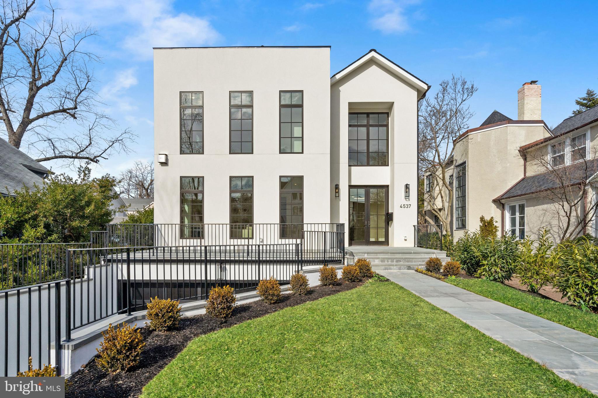Monument Builders proudly unveils 4537 Lowell St NW, a newly constructed masterpiece that showcases a reimagined Contemporary-style home with 6 Bedrooms, 5 Full Baths, and 2 Half Baths, and an oversized 2-Car Garage. Delivering 6,400 finished SF, this California-style dream home is unforgettable with its and perfectly placed windows, incredible Nano doors that extend the Family Room outside oversized to the expansive yard, and extraordinary hand-picked marble features. A wood-paneled elevator gives access to all 4 floors. The exceptional outdoor spaces include a large patio that pours out into the level yard, two rooftop decks, and a front porch. Nestled in Wesley Heights on coveted Lowell Street, this exciting home sparkles with a desirable southern exposure and a stylish vibe that suits a modern lifestyle.   Intricate custom millwork and herringbone hardwood floors accent the Foyer and the thoughtful floor plan invites you to explore the expert craftsmanship and magnificent quality that is apparent throughout the entire home. Gorgeous sightlines are everywhere, beginning with a striking view from the Foyer that carries directly through the home to showcase a glimpse of the Patio through the rear folding doors. Dramatic 10'+ ceilings make quite the lasting impression as you travel through the main entertaining spaces. The formal Living Room is flooded with natural light through 3 large south-facing windows and the entire space is warmed by a modern gas fireplace.   The Dining Room is dressed in decadent molding and showcases a built-in buffet and secondary access to the huge Pantry. One of the most impressive areas is the Family Room, a space that was designed with intimate gatherings as well as large events in mind. The Family Room is centered by a gas fireplace with a marble slab surround that carries all the way up to the coffered ceilings. A wall of Nano doors dovetails the indoor and outdoor spaces, creating a remarkable atmosphere. The adjoining Kitchen and Breakfast Area are complete with an elegant marble waterfall island, paneled appliances, custom cabinetry, and a large walk-through Pantry.   There are 4 Bedrooms on the First Upper Level, each of which has access to an En-Suite Bath. The Primary Suite is comprised of a spacious Bedroom that overlooks the backyard, two walk-in closets with wall-to-wall custom built-ins, and a luxurious Bath. The Primary Bath boasts a Wet Room with a soaking tub and a shower, a dual vanity, and a Water Closet. The second Bedroom Suite has a walk-in closet and a private Bath. Bedrooms #3 and #4 have tray ceilings and share a "Jack and Jill" style Bath. There is a secondary Laundry Room on this level.   The Second Upper Level is highlighted by 2 Roof Decks and a Party Room with a beautifully designed Bar that houses an Ice maker and a Beverage Refrigerator in a spacious custom-made cabinet. This room has an En-Suite Bath and may also be used as a Guest Suite, Office, or Home Gym. Outdoor deck space makes up approximately half of the top floor footprint, a feature that is not often found but absolutely treasured.  Additional living space is on the Lower Level including a Recreation Room, Bedroom Suite with a Full Bath, and a Laundry Room with a Pet Shower. There is access to the oversized 2-Car Garage from this level along with a walkout to stairs that lead up to the yard.