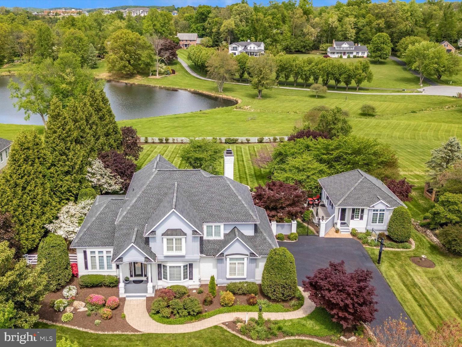 This is truly a remarkable one-of-a-kind home, situated on a magnificently landscaped 1.08  lot overlooking a lake in the The Greens, a small community of upscale homes on estate lots, one of Frederick's most sought-after neighborhoods. With over 6700 square feet of impressively finished living space, this spectacular home is a superb blending of luxury, comfort, style, and livability. - ideal for large or small gatherings of family and friends. This lovely home, which has been almost entirely and meticulously updated over the past several years, only enhancing the features of the original home, must be experienced to be fully appreciated. The main house contains an impressive two-story foyer entrance, first-floor office, chef’s kitchen with custom cabinetry and oversized island highlighted with Calcutta Quartzite Counter Surfaces, 4 bedrooms, 4.5 baths,  gleaming hardwood floors, fully finished basement, two fireplaces and a 3 car attached garage. The family room accesses the rear deck offering spectacular panoramic views of the lake and vast horizon. The rear yards landscaped is picturesque with extensive, elaborate hardscaped patios, walkways, seating areas, and a tranquil Koi Pond with a rippling waterfall. Off the kitchen is a cozy, shaded screened porch with an outdoor grilling station. The separate 2- story guest house is equally lovely with an extra bedroom, a fifth full bath, a kitchenette, and a private deck overlooking the lake. The finished lower level features a home wellness spa/gym including an 8-person sauna. Available for showings by appointment