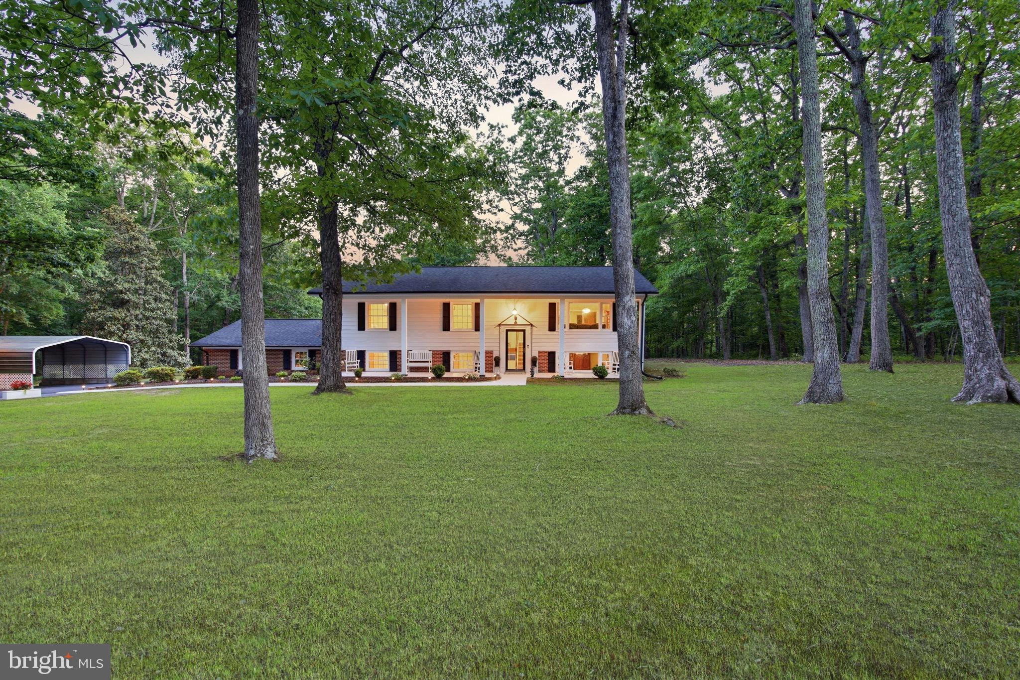 Welcome to this charming home tucked away on 6 beautiful private acres in a quiet yet convenient Spotsylvania County location! Offering the perfect combination of comfort, privacy, and space, this property truly feels like your own private retreat while still being close to schools, shopping, commuter lots, dining, and so much more.

Step inside to find a spacious eat-in kitchen featuring granite countertops, new stainless steel appliances, ceramic tile flooring, built-in seating, and plenty of room for gathering and entertaining. The adjoining dining area offers laminate flooring and flows nicely into the spacious family room filled with natural light.

One of the standout features of this home is the incredible all-season sunroom. Complete with ceramic tile flooring, a ceiling fan, and walls of windows, this relaxing space overlooks the gorgeous wooded backyard and offers peaceful views with exceptional privacy year-round.

Outdoor living is just as impressive with a multi-level deck featuring wrought iron railings leading down to a large lower-level concrete patio — perfect for entertaining, relaxing, or simply enjoying the beauty of the property.

Additional interior features include:
• New carpet throughout
• Spacious bedrooms
• Updated bathrooms
• Pantry closet
• Ceiling fans throughout
• Large primary suite with beadboard accents, updated lighting, newer sink, and ceramic tile in the primary bath

The finished lower level offers an oversized recreation room with a fireplace, a huge 4th bedroom, and a 3rd full bath — making it ideal for guests, multi-generational living, or additional entertaining space. The lower level also features vinyl laminate flooring, a laundry area with a storage closet, and walk-out access to the patio and oversized two-car garage.

The side-load two-car garage includes built-in cabinets, attic access, and automatic garage door openers.

Outside, the property is truly exceptional. Enjoy a long recently resurfaced paved driveway, covered aluminum carport, and a charming older barn/shed perfect for lawn equipment, hobbies, storage, or workshop space. The wooded acreage offers endless possibilities and incredible privacy.

The sellers have shown tremendous pride of ownership throughout the years with numerous updates including:
• Newer roof
• Newer windows
• Updated plumbing throughout
• Newer well pump
• Fresh paint throughout
• Jetted tub
• Replaced interior doors
• Newer garage door

There is truly nothing to do but move in and enjoy this peaceful property. If you are looking for privacy, acreage, and a well-maintained home in a fantastic Spotsylvania location, this one is a must-see!
