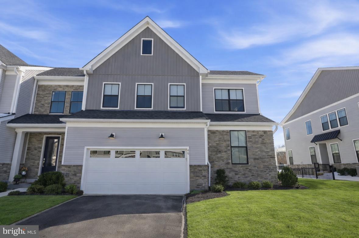 Welcome to 49 Tradesville Drive where luxury meets modern day low maintenance living.  This Vetri Aberdeen model by Toll Brothers is a luxury end-unit home  with private front entry that offers refined finishes, upgraded lighting, and a thoughtfully designed open layout. The main level welcomes you with a dramatic two-story foyer and an expansive great room featuring floor to ceiling windows which provides natural light, a striking fireplace accented by black granite surround and wood detail, a bright dining area opens to a partially covered 600 sqft deck with privacy panels and multiple seating areas with an additional outdoor gas firepit and extended entertaining space with built-in tankless BBQ grill. Back inside, the gourmet kitchen is truly stunning, showcasing quartzite countertops, a white apron-front sink, extensive pantry storage, premium stainless-steel appliances, and a large center island with seating. Designed for the home chef, the kitchen also features a 6-burner gas range, custom exhaust hood, and a wet/dry bar with built-in temperature-controlled wine fridge. Engineered hardwood flooring flows throughout the main living areas. The first-floor primary suite offers a spacious walk-in closet and a spa-like bath with granite surfaces, frameless glass shower enclosure, and a double vanity with dedicated makeup area. A well-appointed laundry room with front-load washer and dryer and cabinetry adds convenience and additional storage while a custom mudroom with bench seating and half bath completes the main level. Upstairs, two additional bedrooms with generous closets share a full hall bath centered around a versatile loft space used as a secondary living area that looks below the great room. A finished, carpeted bonus room—currently used as a kids’ playroom—features recessed lighting and a remote-controlled ceiling fan, offering flexible living space. The home also includes abundant recessed lighting throughout and elegant light fixtures. The additional 1000 sq ft unfinished basement provides excellent storage and future living space potential, with plumbing already in place for a full bathroom. Enjoy a peaceful setting with private wooded views and direct access to the community walking trails. Minutes from downtown Doylestown's restaurants, shops, train station, cultural museums & more. This home is truly turn-key and ready for its next owners!