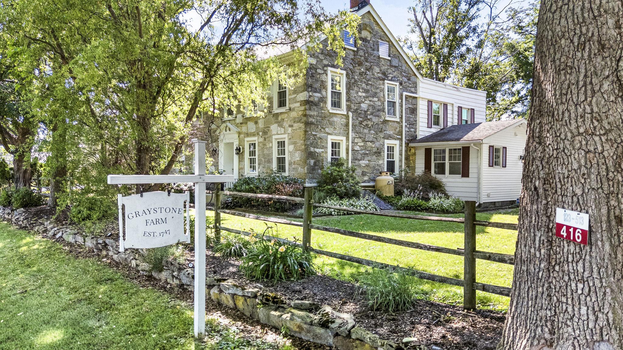 Historic, versatile, and truly one-of-a-kind, Graystone Farm offers nearly 8 scenic acres in the Schuylkill Valley School District with a rare blend of residential charm, rural beauty, and flexible outbuilding space. The property is anchored by a historic stone farmhouse and surrounded by open, level acreage, fenced pasture areas, perennial gardens, a greenhouse, and established pear, plum, and persimmon trees. A remarkable walnut tree, believed to be centuries old, adds to the timeless setting.

Currently used as a private residence, small farm, and established wedding venue, the property offers impressive infrastructure for a buyer seeking space for animals, hobbies, creative work, equipment storage, or potential continuation of the existing wedding venue use. The bank barn includes a finished, soundproofed suite with recessed lighting and modern flooring, ideal for a private office, studio, dressing area, or flex space. The heated venue area features rustic character and multiple heat sources, creating a welcoming setting for gatherings across more of the year. The lower level offers a heated workshop area with custom cabinetry, compressed air and dust collection infrastructure, and substantial room for projects, equipment, and storage. With three garage doors and room for 4+ vehicles or equipment, the barn provides exceptional functionality.

Inside the farmhouse, historic character is balanced by thoughtful updates and flexible everyday living. Features include exposed beams, wood floors, a brick fireplace, updated quartz countertops, spacious living areas, a large mudroom, main-level laundry, and ductless mini-split comfort. The home is currently configured with 4 bedrooms, including a main-level bedroom/sunroom option, plus additional areas well suited for office, guest, or creative use. The residence includes 2 full baths, with an additional half bath located in the venue/barn area. A large walk-up attic with generous ceiling height provides excellent storage and future finishing potential.

Additional features include multiple outbuildings, fenced animal areas, a historic summer kitchen currently used as a private lounge, and a dedicated utility pad with water and electric service for venue support. Conveniently located just minutes from Routes 61 and 222, this rare property offers space, character, and opportunity in a setting that is difficult to duplicate. For added peace of mind, the seller is offering a one-year America’s Preferred Home Warranty with an acceptable offer.