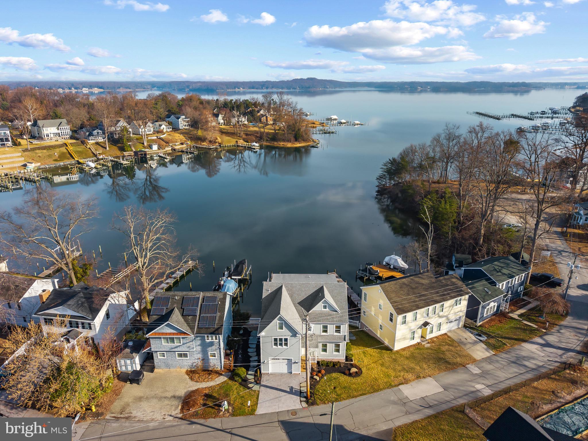 Perched along the waterfront of Cool Spring Cove, this thoughtfully enhanced residence delivers a seamless blend of comfort, recreation, and effortless coastal living, where extensive upgrades elevate both daily enjoyment and entertaining. The outdoor environment has been carefully curated to maximize time on and around the water, with redesigned hardscaping, custom lighting, lush landscaping, and irrigation creating a polished yet low-maintenance setting. Expansive multi-level decking invites gatherings of every scale, featuring a fully rebuilt lower deck with a private hot tub retreat and sleek, unobstructed railings that preserve water views, while the upper deck’s remote-controlled awning allows for shaded relaxation during warm summer afternoons.

The private pier system transforms the property into a true boating and waterfront lifestyle hub, featuring a 12,000-lb boat lift capable of accommodating a substantial vessel, dual jet ski lifts for spontaneous adventures, upgraded electrical service, and convenient water access via an integrated ladder. Thoughtful additions such as docking bumpers, cleats for visiting boaters, and live well and crabbing accommodations create the ideal setting for sunset cruises, weekend water sports, and enjoying the Chesapeake’s renowned crabbing traditions. 

Inside, extensive interior enhancements enrich everyday living while providing exceptional spaces for hosting. The main level layout flows seamlessly from the dining area, living room with fireplace and the spectacular white kitchen with large island and fabulous views. The finished lower level is designed as an entertainment destination, showcasing a custom bar with refrigeration, keg chiller, dishwasher, and ice maker, along with a theater room, gathering lounge, and spa-inspired full bath that offers guests and residents alike a resort-style experience. 

The primary suite boasts exceptional water views and provides a luxurious escape with cherry hardwood flooring, custom closet, conveniently located laundry room and a stunning spa-like bath with free-standing soaking tub overlooking the water. 2 additional bedrooms on this level and an expansive additional upper level with full bath, views and plenty of space; provides ample options for accommodating family and friends. 

Together, these extensive improvements create a turnkey waterfront sanctuary designed to support an active boating lifestyle, memorable entertaining, and relaxed everyday living. Welcome Home!