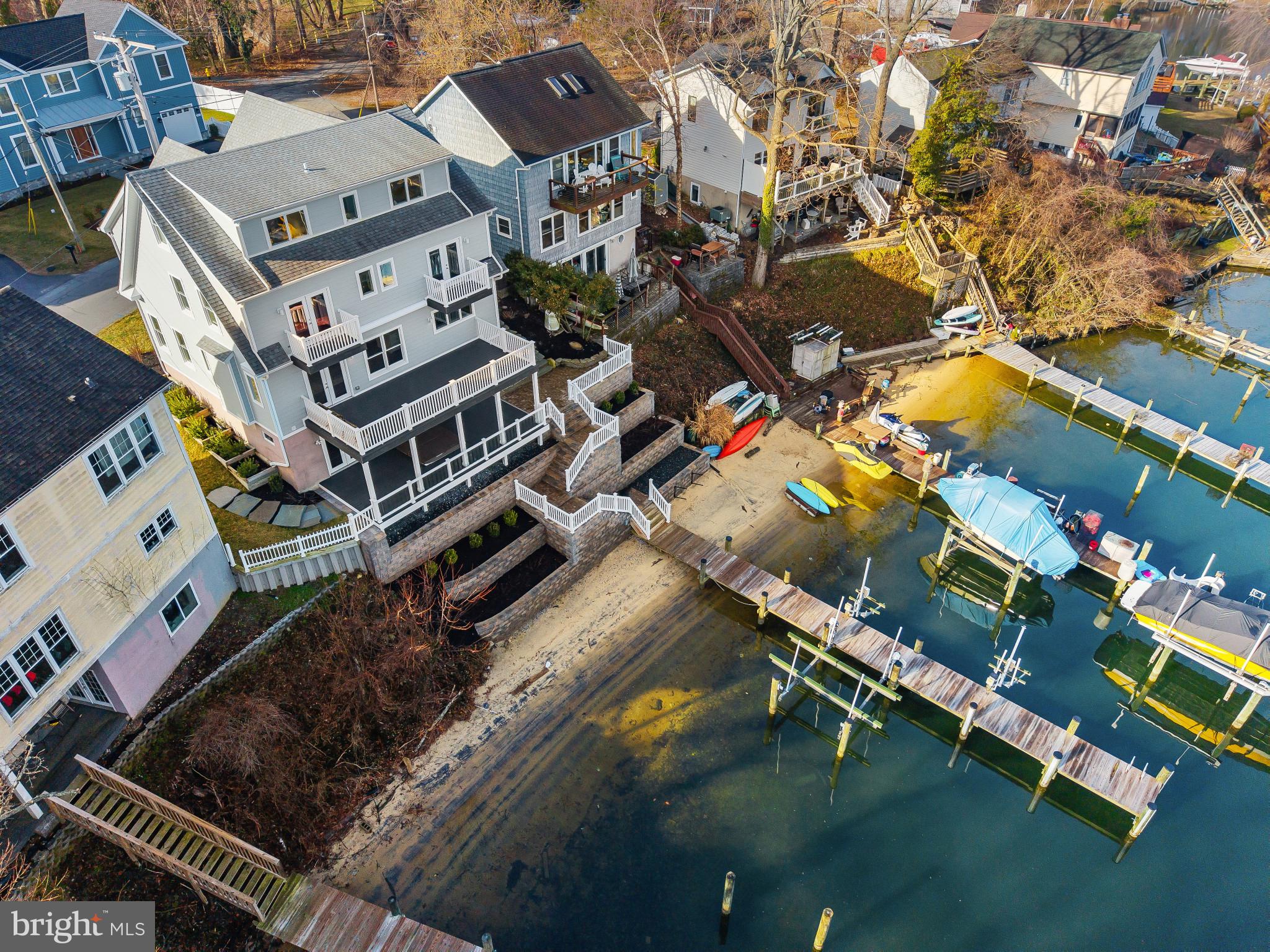 Perched along the waterfront of Cool Spring Cove, this thoughtfully enhanced residence delivers a seamless blend of comfort, recreation, and effortless coastal living, where extensive upgrades elevate both daily enjoyment and entertaining. The outdoor environment has been carefully curated to maximize time on and around the water, with redesigned hardscaping, custom lighting, lush landscaping, and irrigation creating a polished yet low-maintenance setting. Expansive multi-level decking invites gatherings of every scale, featuring a fully rebuilt lower deck with a private hot tub retreat and sleek, unobstructed railings that preserve water views, while the upper deck’s remote-controlled awning allows for shaded relaxation during warm summer afternoons.

The private pier system transforms the property into a true boating and waterfront lifestyle hub, featuring a 12,000-lb boat lift capable of accommodating a substantial vessel, dual jet ski lifts for spontaneous adventures, upgraded electrical service, and convenient water access via an integrated ladder. Thoughtful additions such as docking bumpers, cleats for visiting boaters, and live well and crabbing accommodations create the ideal setting for sunset cruises, weekend water sports, and enjoying the Chesapeake’s renowned crabbing traditions. 

Inside, extensive interior enhancements enrich everyday living while providing exceptional spaces for hosting. The main level layout flows seamlessly from the dining area, living room with fireplace and the spectacular white kitchen with large island and fabulous views. The finished lower level is designed as an entertainment destination, showcasing a custom bar with refrigeration, keg chiller, dishwasher, and ice maker, along with a theater room, gathering lounge, and spa-inspired full bath that offers guests and residents alike a resort-style experience. 

The primary suite boasts exceptional water views and provides a luxurious escape with cherry hardwood flooring, custom closet, conveniently located laundry room and a stunning spa-like bath with free-standing soaking tub overlooking the water. 2 additional bedrooms on this level and an expansive additional upper level with full bath, views and plenty of space; provides ample options for accommodating family and friends. 

Together, these extensive improvements create a turnkey waterfront sanctuary designed to support an active boating lifestyle, memorable entertaining, and relaxed everyday living. Welcome Home!