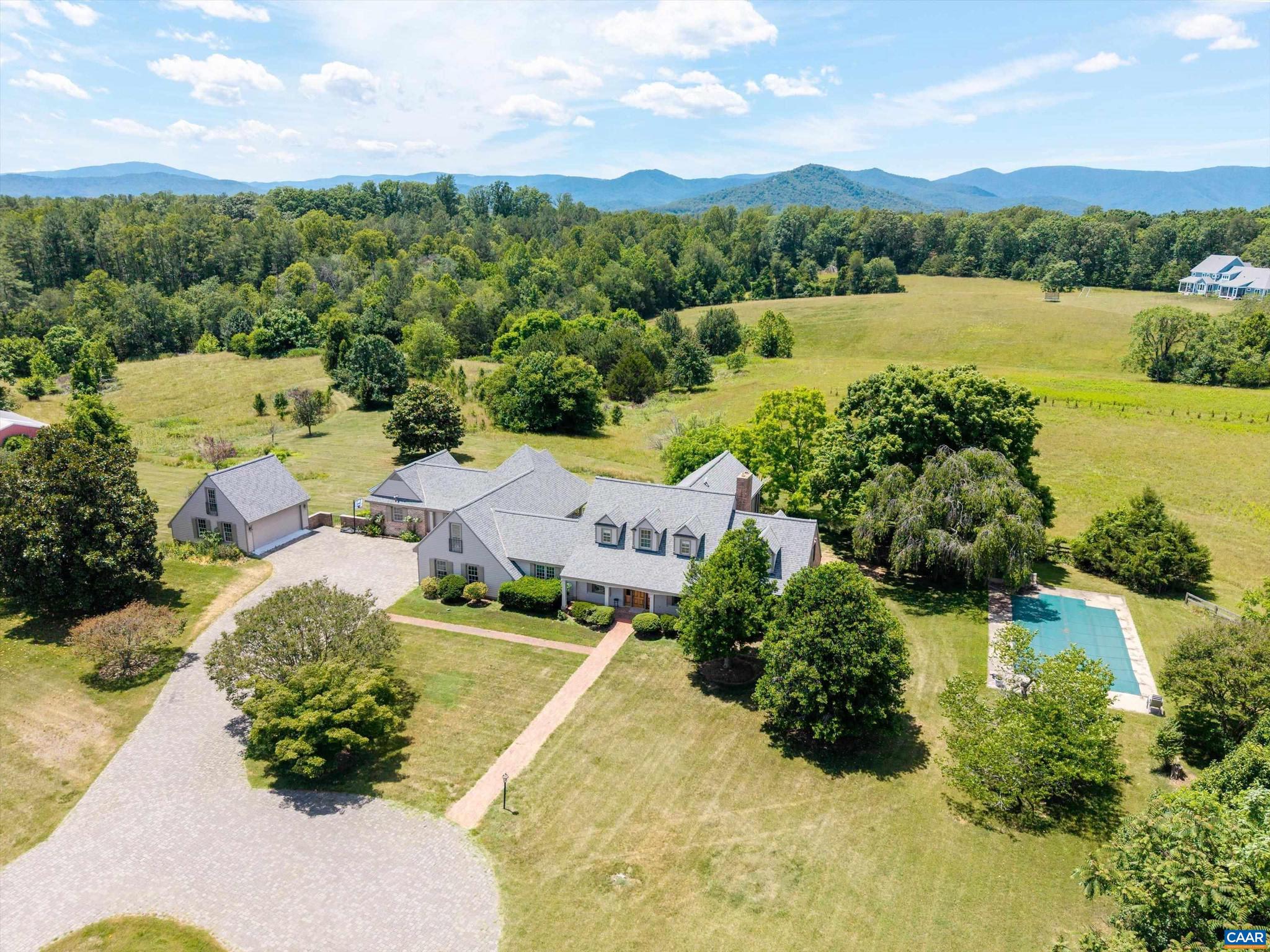 Framed by breathtaking vista views and set on approximately 21 pristine acres, this exceptional country estate offers a lifestyle defined by beauty, privacy, and timeless sophistication.  This is more than a home - it's a legacy Virginia Countryside property.  From the moment you travel down the tree-lined and hand-laid paver drive, you're welcomed into a setting that feels worlds away, yet only minutes from the conveniences of Charlottesville.  Thoughtfully positioned, the residence is surrounded by rolling meadows that create a spectacular backdrop in every season. Thoughtfully designed for everyday living and elegant entertaining, the home seamlessly blends classic architecture with inviting indoor and outdoor spaces.  Enjoy the private in-ground pool and outdoor space where mornings begin wondrously and evenings conclude beneath brilliant Virginia skies. Second garage provides exceptional flexibility for vehicles, hobbies, or future expansion.  Whether your vision includes horses, gardening, a vineyard, or simply enjoying the tranquility of your own retreat, the property offers endless possibilities while preserving the remarkable sense of space/seclusion. Partial ownership to a stocked, private 2 acre pond on edge of lot .