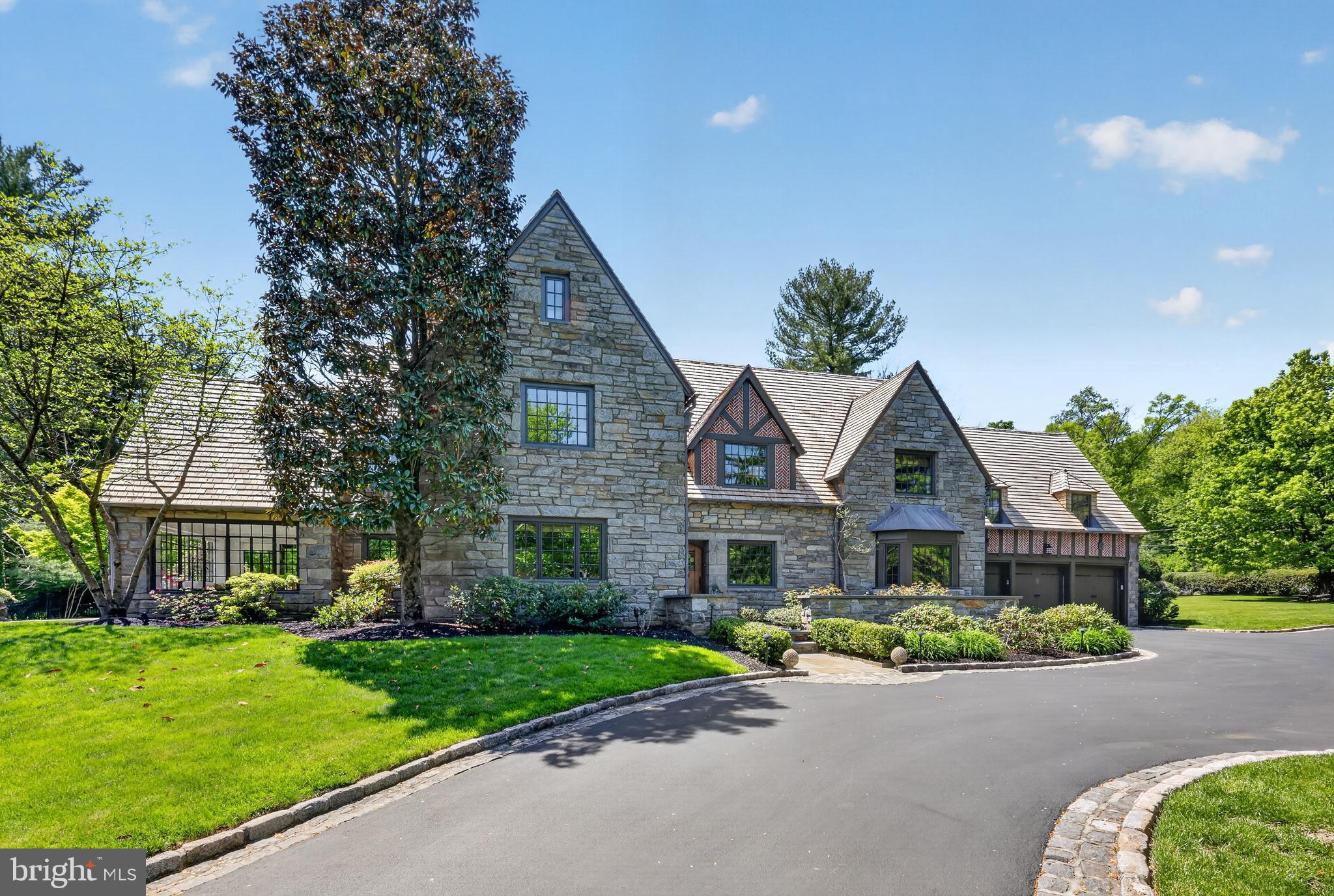 Welcome to 56 Tunbridge Road, a timeless 1930s English Tudor located in one of the Main Line’s most coveted neighborhoods. Over the past 14 years, the home has been meticulously maintained and improved, following a significant renovation designed by Peter Zimmerman Architects 2004–2005. The result is a charming, &  sunny home that has, and will stand the test of time. Upon arrival, two recent upgrades are immediately evident: the new cedar shake roof (2025) and Pella Architectural Windows (2014). A pillared entrance leads to this impeccable 5 bedroom, 4 full and 2 half bath home with an expansive terrace overlooking the  one acre level lawn. Inside is a bright, 3 story center hall colonial with wonderful circulation for entertaining. Many rooms feature Tudor inspired details, hardwood floors, classic millwork, custom built ins, and arched doorways. The first floor includes a foyer opening to the living and dining rooms, all with ornate plaster crown molding & hardwood floors. Off the living room—featuring a fireplace and French doors to the terrace—is a library with hand rubbed cherry paneling & a Mercer tile fireplace. A sunroom with terrace access sits beyond. The dining room offers a bay window, custom wainscoting, &  access to the butler’s pantry/bar. A lighted gallery with limestone floors & three sets of steel French doors leads to the kitchen, powder room, mudroom/family entrance from the garage, & potting room. The kitchen includes custom cabinetry, quartz countertops and backsplash, a large natural oak storage cabinet, large island with refrigerated drawers, Wolf 6 burner cooktop with pasta arm, Wolf double ovens & warming drawer, Bosch dishwasher, Sub Zero refrigerator, & two additional sets of steel French doors to the terrace. Adjacent are the mudroom with home office workspace, coat closet, & potting room with flagstone floor & double sink. A secondary staircase connects to the second floor. The butler’s pantry includes a Sub Zero wine cooler, Uline beverage refrigerator, and access to the full unfinished basement.
The second floor includes the primary suite with large bedroom, dressing room with 3 walk-in closets, spacious bath with double vanity, whirlpool tub, shower, water closet, & a separate sitting room. Four additional bedrooms include two with ensuite baths & two sharing a hall bath. The laundry room is also on this level.
The finished third floor offers flexible space for an office, studio, playroom, or gym, along with custom cabinetry  & a large walk-in cedar closet. The full basement remains unfinished & includes a half bath and Bilco doors to the backyard.
Additional recent improvements include: refreshed kitchen and powder room, newer HVAC systems; boilers (2013 & 2025) for steam, hot water & radiant heat, central air (2022), new gas and water lines, and a Generac whole house generator (2018).
This remarkable property offers a rare combination of architectural character, modern updates, and premier Main Line access. Morning walks wind along quiet, tree lined roads past  two of the region’s most storied landscapes: Merion Golf Club - host to many USGA Championships including the 126th U.S. Amateur this August  &  Haverford College’s  Nature Trail, home to one of the nation’s oldest planned collegiate landscapes.  All of this,  in addition to easy access to Haverford and Ardmore SEPTA/Amtrak stations, Suburban Square, top ranked schools, private clubs, and Philadelphia International Airport, confirm this home offers the most exceptional Main Line lifestyle.