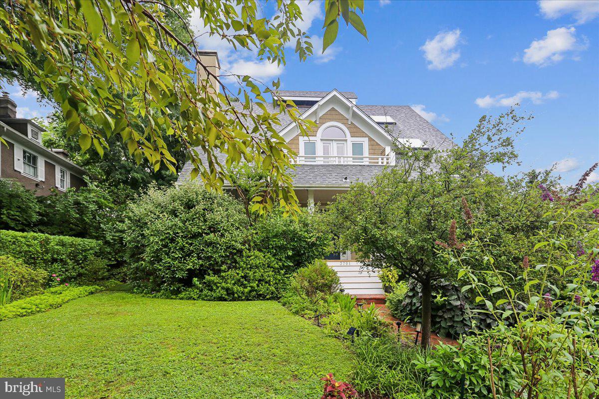 Nestled on a picturesque corner lot in one of Chevy Chase’s most coveted, walkable enclaves, this magnificent residence—masterfully designed by Paul Treseder—perfectly blends timeless elegance with modern luxury.

A lush canopy of mature greenery lines the front walkway, welcoming you to a spacious, covered front porch complete with a classic two-person swing. Stepping through the distinct blue front door, you are greeted by a stately main level adorned with rich hardwood floors, crown molding, and architectural columns.

To the left, a grand, open living and dining area features a cozy wood-burning fireplace, while to the right, a sophisticated home office/library boasts a wall of custom built-in shelving and sun-drenched bay windows overlooking the porch.

At the heart of the home is a spectacular 2020 rear expansion designed for effortless gathering and high-end entertaining. The gourmet kitchen is anchored by an expansive custom island with a prep sink, three walls of extraordinary Jack Rosen cabinetry, premium stainless steel appliances—including a double wall oven, built-in range, and wine refrigerator—and an abundance of counter space.

A step down leads to a charming breakfast nook with built-in bench seating, which flows seamlessly into a dramatic, skylit family room defined by soaring vaulted ceilings, a brick fireplace, and direct access to a convenient mudroom.

The upper levels offer an unparalleled private sanctuary. The second floor features a second bedroom and full bath, alongside a truly palatial primary suite conversion. Here, a former bedroom has been reimagined into a luxurious formal dressing room with custom cabinetry, an island jewelry and beauty table, a skylit sitting area, and double doors opening to a private balcony. The spa-like primary bathroom impresses with vaulted ceilings, an air propulsion soaking tub, and a separate walk-in shower.

On the top level, you will find two additional generously sized bedrooms equipped with modern solar shades and a stylish shared full bathroom.

The fully finished lower level offers ultimate versatility, boasting potential bedrooms or dedicated workspaces with an independent side walkout entrance—perfect for a quiet, professional home office. This level also features a welcoming recreation room, a full bathroom, a temperature-controlled wine closet, a dedicated workshop/utility room, and a clever vintage-inspired laundry room with a clothes drop hatch connected directly from the primary suite.

The outdoor oasis is equally enchanting, featuring a shaded rear flagstone patio enveloped by lush perennials, privacy fencing, and a side lawn ideal for pets. Adding to the property's versatility is a detached carriage garage with a carpeted upper level, perfect for a playroom, studio, or private guest suite. Situated just moments from the premier dining, shopping, and Metro access of downtown Bethesda, the scenic trails of Rock Creek Park, and the prestigious Chevy Chase and Columbia Country Clubs, this extraordinary property offers a rare combination of location, scale, and sophisticated design.