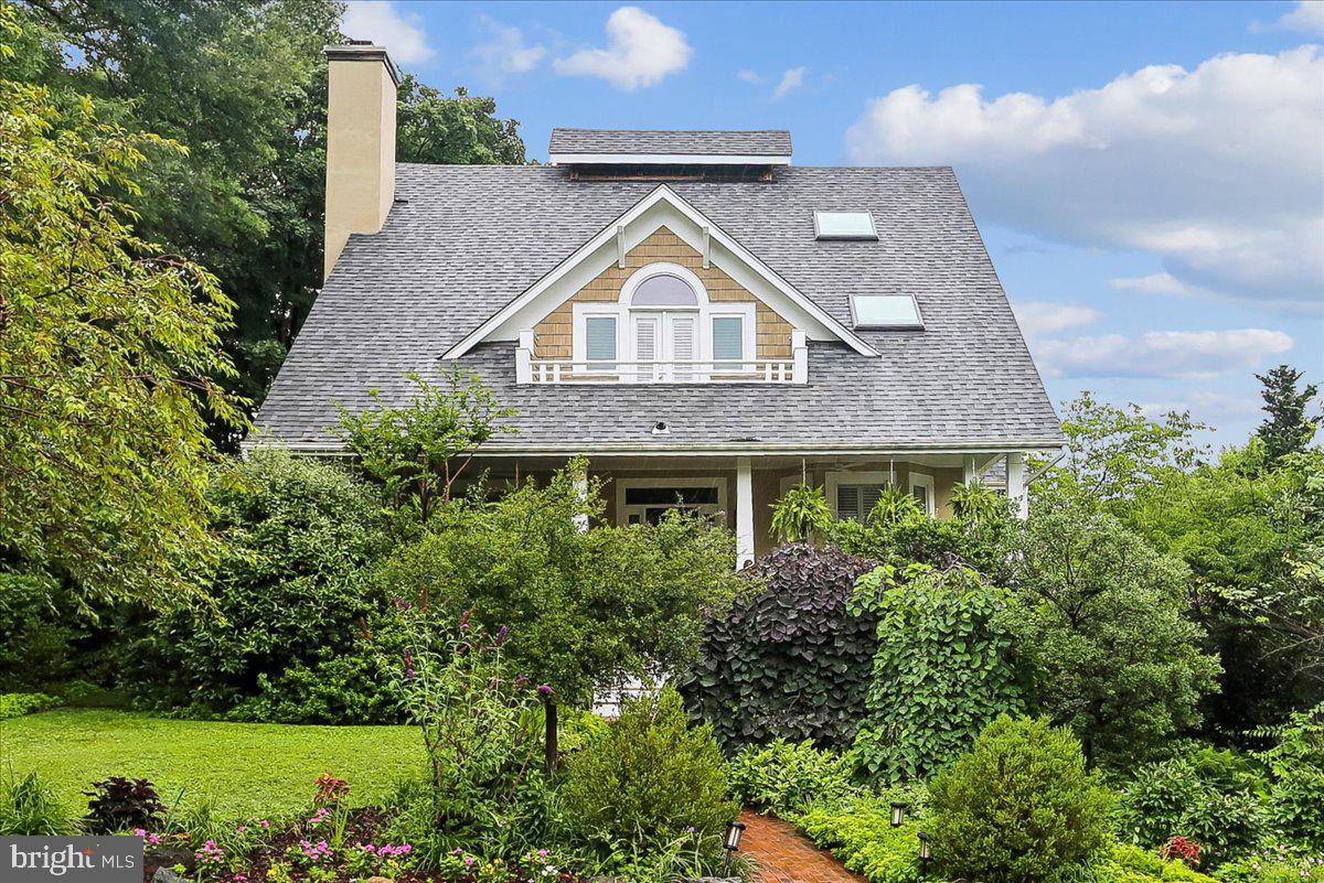 Nestled on a picturesque corner lot in one of Chevy Chase’s most coveted, walkable enclaves, this magnificent residence—masterfully designed by Paul Treseder—perfectly blends timeless elegance with modern luxury.

A lush canopy of mature greenery lines the front walkway, welcoming you to a spacious, covered front porch complete with a classic two-person swing. Stepping through the distinct blue front door, you are greeted by a stately main level adorned with rich hardwood floors, crown molding, and architectural columns.

To the left, a grand, open living and dining area features a cozy wood-burning fireplace, while to the right, a sophisticated home office/library boasts a wall of custom built-in shelving and sun-drenched bay windows overlooking the porch.

At the heart of the home is a spectacular 2020 rear expansion designed for effortless gathering and high-end entertaining. The gourmet kitchen is anchored by an expansive custom island with a prep sink, three walls of extraordinary Jack Rosen cabinetry, premium stainless steel appliances—including a double wall oven, built-in range, and wine refrigerator—and an abundance of counter space.

A step down leads to a charming breakfast nook with built-in bench seating, which flows seamlessly into a dramatic, skylit family room defined by soaring vaulted ceilings, a brick fireplace, and direct access to a convenient mudroom.

The upper levels offer an unparalleled private sanctuary. The second floor features a second bedroom and full bath, alongside a truly palatial primary suite conversion. Here, a former bedroom has been reimagined into a luxurious formal dressing room with custom cabinetry, an island jewelry and beauty table, a skylit sitting area, and double doors opening to a private balcony. The spa-like primary bathroom impresses with vaulted ceilings, an air propulsion soaking tub, and a separate walk-in shower.

On the top level, you will find two additional generously sized bedrooms equipped with modern solar shades and a stylish shared full bathroom.

The fully finished lower level offers ultimate versatility, boasting potential bedrooms or dedicated workspaces with an independent side walkout entrance—perfect for a quiet, professional home office. This level also features a welcoming recreation room, a full bathroom, a temperature-controlled wine closet, a dedicated workshop/utility room, and a clever vintage-inspired laundry room with a clothes drop hatch connected directly from the primary suite.

The outdoor oasis is equally enchanting, featuring a shaded rear flagstone patio enveloped by lush perennials, privacy fencing, and a side lawn ideal for pets. Adding to the property's versatility is a detached carriage garage with a carpeted upper level, perfect for a playroom, studio, or private guest suite. Situated just moments from the premier dining, shopping, and Metro access of downtown Bethesda, the scenic trails of Rock Creek Park, and the prestigious Chevy Chase and Columbia Country Clubs, this extraordinary property offers a rare combination of location, scale, and sophisticated design.