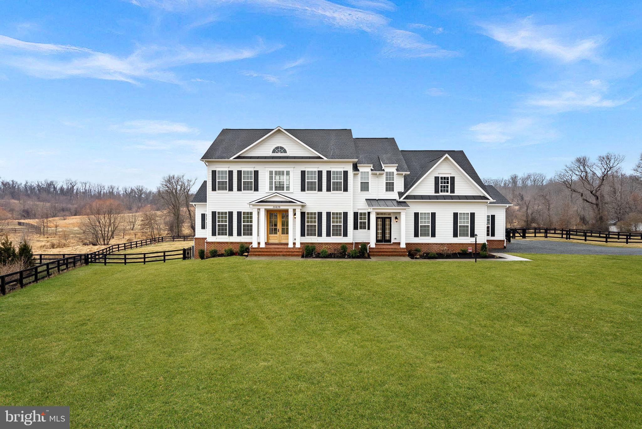 Set on 16 breathtaking conservancy acres in Purcellville,  this exceptional home offers timeless architecture, refined interiors, and the peaceful lifestyle Western Loudoun is known for. With HOA approval for horses and surrounding protected land, the property offers rare privacy, open space, and scenic pastoral views.

A long private drive leads to the stately white colonial, where a welcoming front porch and sweeping countryside vistas create striking curb appeal. Built by renowned Carrington Homes, the Kendall Lane model is celebrated for its craftsmanship, elegant design, and thoughtfully designed living spaces.

Inside, a gracious foyer welcomes you with rich hardwood floors, detailed trim work, and a beautifully crafted staircase. Arched openings, elegant moldings, and beautiful solid wood French doors that frame views of the surrounding landscape add warmth and architectural character throughout the home, while expansive living areas create an effortless flow between spaces.

At the heart of the home is a stunning chef’s kitchen designed for both entertaining and daily life. Featuring expansive quartzite countertops, custom white cabinetry, double wall ovens, a statement range hood, and an oversized center island with seating, the kitchen opens seamlessly to the family room and sun-filled morning room where walls of windows frame tranquil views of the surrounding acreage.

The family room is a true showpiece, featuring an elegant coffered ceiling, a beautiful fireplace that anchors the space, and large windows that fill the room with natural light. 

A main-level bedroom with a full en suite bath provides the perfect space for guests, extended family, or a private home office.

Upstairs, the luxurious primary suite offers a true retreat, complete with a tray ceiling, hardwood floors, and a spacious sitting area highlighted by an elegant arched window overlooking the property. The spa-inspired primary bath features dual vanities, a freestanding soaking tub centered beneath an arched window, and a large walk-in shower with elegant tile surround.

The finished lower level provides additional space for recreation, entertaining, fitness, or media. 

This remarkable property offers the rare combination of luxury living, protected land, and countryside charm—just minutes from Purcellville’s charming downtown, wineries, breweries, and farm markets.