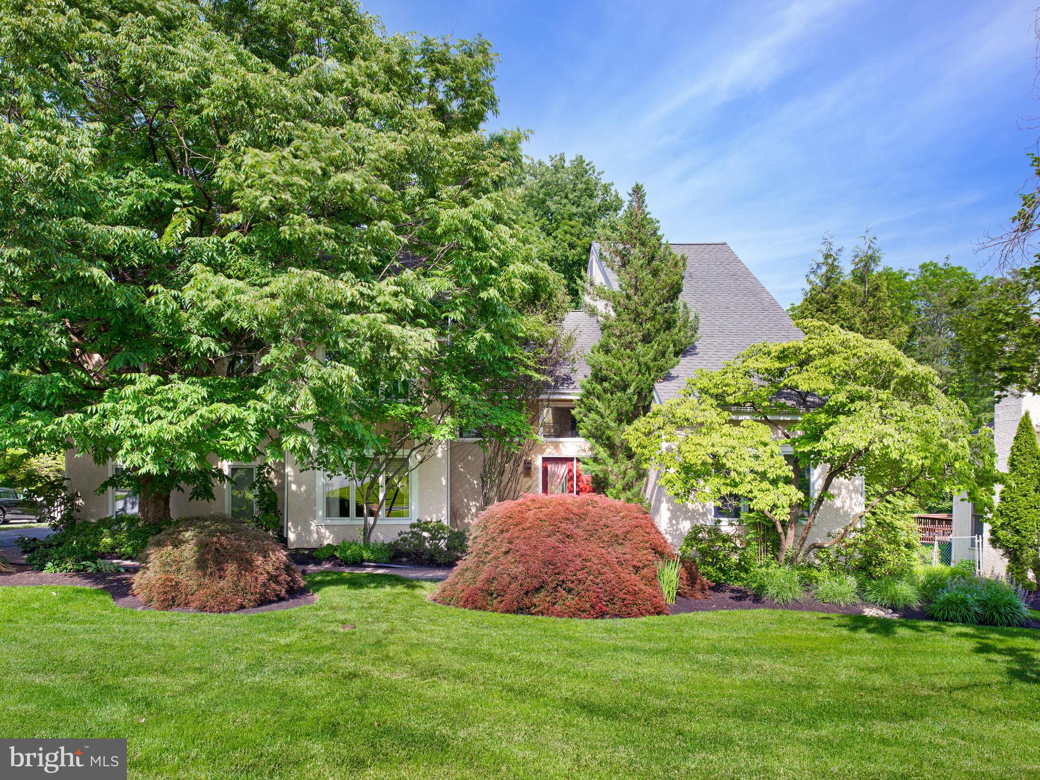 543 Foxglove Lane occupies one of the most desirable settings in Indian Creek, where open grounds at the rear reach to private woodland, a mature tree line wrapping the property in privacy. A tiered hardwood deck overlooks the lawn beneath a lattice-screen pergola drawn from Japanese garden design, an outdoor room this neighborhood rarely offers.

 Inside, the house is built around light and volume. A two-story great room rises to a skylit cathedral ceiling, anchored by a stone fireplace and crossed above by a second-floor bridge whose iron railing matches the open staircase. Arched passages carry the room to the entry on one side and the kitchen on the other. The kitchen centers on a curved granite island over a stone-clad base, travertine flooring continuing into a vaulted breakfast room: twin skylights, a curved bay of windows reaching into the trees, and a glass door to the deck.

The main level continues with a dining room under alabaster pendant light and a library lined on three sides with floor-to-ceiling mahogany bookcases. A full bath nearby lets the library serve as a main-floor bedroom or guest suite. Upstairs, five bedrooms include a primary suite set apart in its own wing, vaulted, with private bath and walk-in closet. The finished lower level is daylit and walks out to the grounds, adding a recreation room, a sixth bedroom with egress window, and a full bath.

 The home sits within Lower Merion School District, minutes from the hospitals, the main transportation routes, the area’s shopping and dining, and the Center City commute.