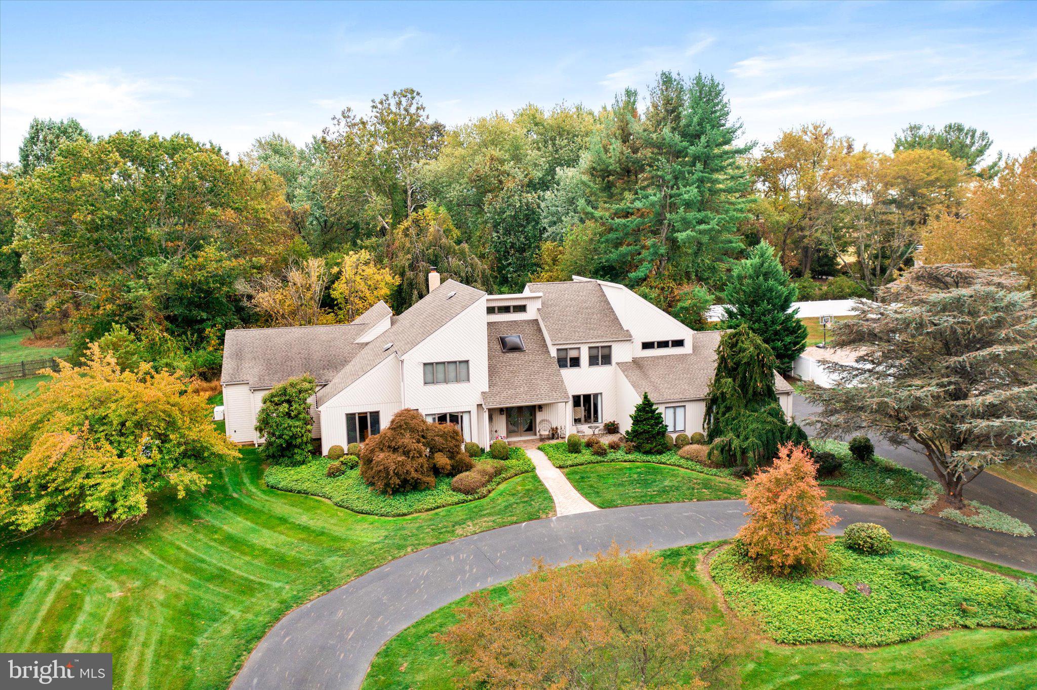 A rare offering has come to the market!
Situated on a beautiful street in a coveted neighborhood in Yardley, this contemporary has it all. Set back on an acre lot of professionally planted and maintained trees and shrubbery, this property offers a breathtakingly beautiful Shangri-la of specimen trees, wooly lamb's ears, and even a fig tree. From the outside, the covered entrance is welcoming and elegant, and inside, the volume ceiling, skylight, and hardwood floor in the gracious entry only hints at the sophisticated modifications and upgrades you will find in this home. A masterfully crafted, eat-in kitchen has everything a chef could want, from the gorgeous cabinetry, to the top of the line appliances and custom tile work, with plenty of room to chat with the cook (and each other) from the granite island. Custom floor and dining area blend together beautifully, and the sliding glass doors create a wall of glass, open to the paved terrace. What a perfect melding of inside and out! Open to the family room, this combination of spaces offers a feeling of congeniality and ease of living found throughout the house.  A wood burning fireplace adds warmth and charm, and glass doors to the terrace make access to the garden inviting and simple. Returning to the entry, another wing beckons.  A convenient study leads to a masterful addition of a lavish main bedroom, creating a private suite. The generous sized bedroom has beautiful built-ins and a lovely window wall plus a gas fireplace The closet is a work of art designed by the current homeowner. Recessed lighting, shelves that go on forever, drawers, a center island, and hanging racks galore, you will always have “room for one more "!  Accessible, beautifully tiled shower, heated floor and custom fittings, walls and vanities add to the already off-the-charts luxury.  You will never need to go upstairs, but if you choose to, there are 4 more bedrooms, including the original main bedroom, so if you want to be on the second floor, you most certainly can. This main bedroom has a cathedral ceiling and fan, and sumptuous bath complete with beautiful custom wood built-ins and granite counters. Stunning tile work is evident in the shower, with a touch of whimsy in the tiling reminiscent of sea stones, and little touches like a built in shelf, 2 shower heads, and recessed soap dish. A private balcony overlooking the gardens makes this second level bedroom another special treat. There are 3 additional bedrooms and a hall bath. Add to all of this a three car, over-sized side entry garage with new EV charger, plus a full basement and full  house generator. Truly a work of art, this property offers everything you want in luxury living, including excellent schools, easy access to transportation, shopping, Princeton and Philadelphia.
Preferred settlement date not before March 2026.