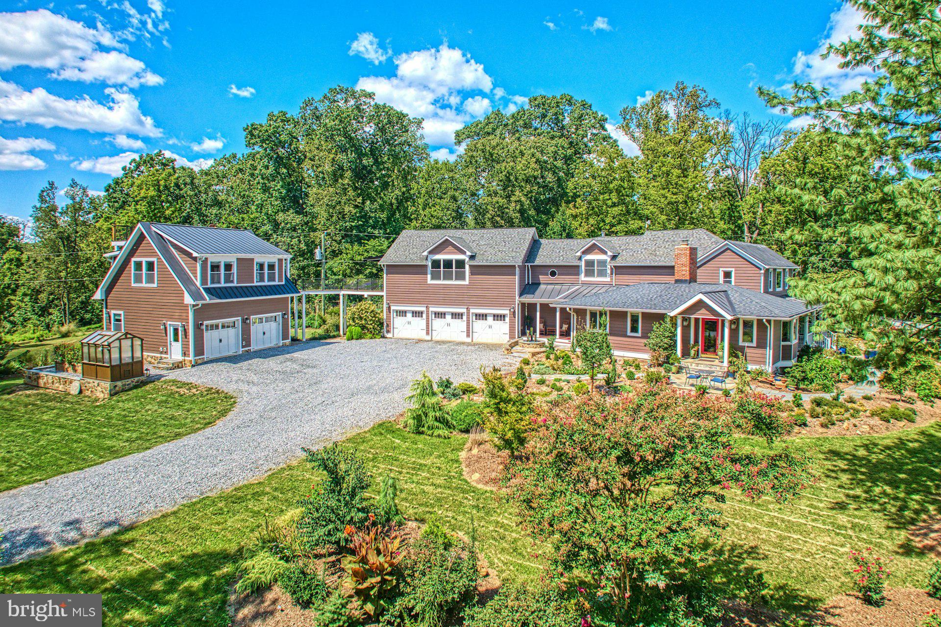 Step into a home where history and modern luxury coexist in perfect harmony. Originally built in 1890 and thoughtfully expanded and renovated, this residence offers over 4,100 sq. ft. of exquisitely designed living space with an oversized 3-car garage. The gated entrance, mountain views, and mature landscaping create a sanctuary of privacy and elegance. Inside, craftsmanship shines at every turn. Rich hardwood floors flow throughout both levels, complemented by custom cabinetry and elegant wainscot detailing. The chef’s kitchen is the centerpiece, boasting a bespoke walnut island with prep sink, two-drawer refrigerator, and abundant storage—ideal for gourmet cooking or effortless entertaining. Gather in the inviting living room, warmed by a wood-burning stove, the cozy family room and anchored by a charming fireplace, or host guests in the spacious main-level bedroom with its own full bath—perfect for multigenerational living, an au-pair, or weekend visitors. Upstairs, the primary suite is a retreat unto itself—generous in scale and impeccably appointed—accompanied by two additional bedrooms with custom built-ins and a versatile bonus room that easily adapts as a home office, studio, or den. Each bathroom is a work of art, designed with timeless finishes worthy of the pages of a luxury design magazine. Beyond the interiors, the estate offers layers of beauty and sophistication. The fully fenced property unfolds with Frank Lloyd Wright–inspired gardens, designed with evergreens and blooming perennials that create year-round visual harmony. A newly constructed detached carriage house provides a flexible studio space—perfect for guests, creative pursuits, or office—connected to the main residence by a dramatic catwalk that marries modern design with historic charm. Outdoor living is where this home truly shines. Two porches invite you to relax and take in panoramic Sugarloaf Mountain views. The dining room and kitchen open seamlessly to beautifully designed patios, perfect for alfresco gatherings. A custom stone fireplace with gas starter, soothing water feature, and subtle exterior lighting set the stage for unforgettable evenings under the stars. The three-acre grounds are as functional as they are enchanting, with expansive lawns offering endless possibilities for recreation and entertaining. All this, just minutes from historic downtown Leesburg, Ida Lee, Morven Park, and Loudoun’s celebrated wineries, restaurants, and boutiques. With easy access to Rt. 7, the Dulles Greenway, and Dulles Airport, your private retreat is never far from convenience