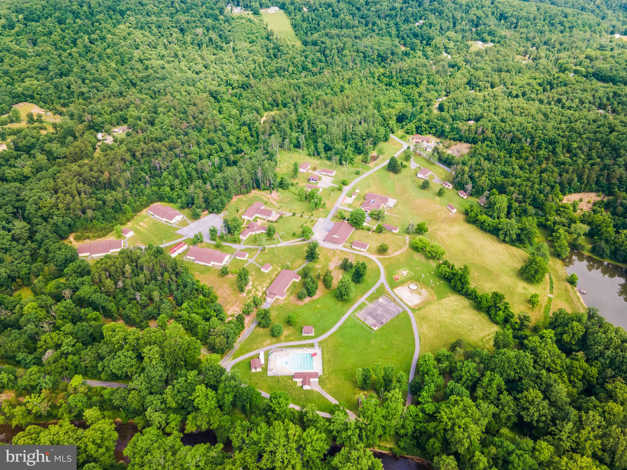 An amazing property being offered for sale on behalf of an international non-profit organization!  Welcome to Camp Tomahawk, a complete, modern retreat center and campground in the beautiful pastoral mountains of West Virginia.  This turnkey, fully operational campground offers everything from high-tech conference and chapel buildings to commercial-grade kitchen, dining, meeting, classroom, and recreational facilities for up to 300 guests.  There are three fully-furnished, comfortable homes for company directors and officials to live in with their families while at the property.  The main conference building itself offers hotel-style rooms for twenty guests, while two additional buildings provide plenty of room for staff housing.  There are three large bunkhouses for campers and counselors, plus a camp caretaker’s residence.  The property is 168 deeded acres and the camp is certified by the American Camp Association (ACA).  Recreational amenities include an event barn for program activities, a swimming pool, a campfire ring with bleacher seating, a pond for fishing and boating, a mountaintop observation tower, several picnic pavilions, two ropes courses, and numerous sports fields and outdoor activity stations.  This secluded retreat is well suited for a variety of corporate, private, and charitable uses, including hosting leadership meetings and staff teambuilding adventures.  It has been serving for 40+ years as a youth campground and is well known and loved by the surrounding communities.  The property is located only 15 minutes from Interstate 81 and Martinsburg, WV and about 30 minutes’ drive from Winchester, VA, Hagerstown, MD, and Charles Town, WV.  Guests will feel their stress melt away as they drive the scenic country roads leading to the camp, leaving behind the crowds and congestion of the daily grind.  When they arrive and turn in through the gates, they’ve found an opportunity to relax and recharge.