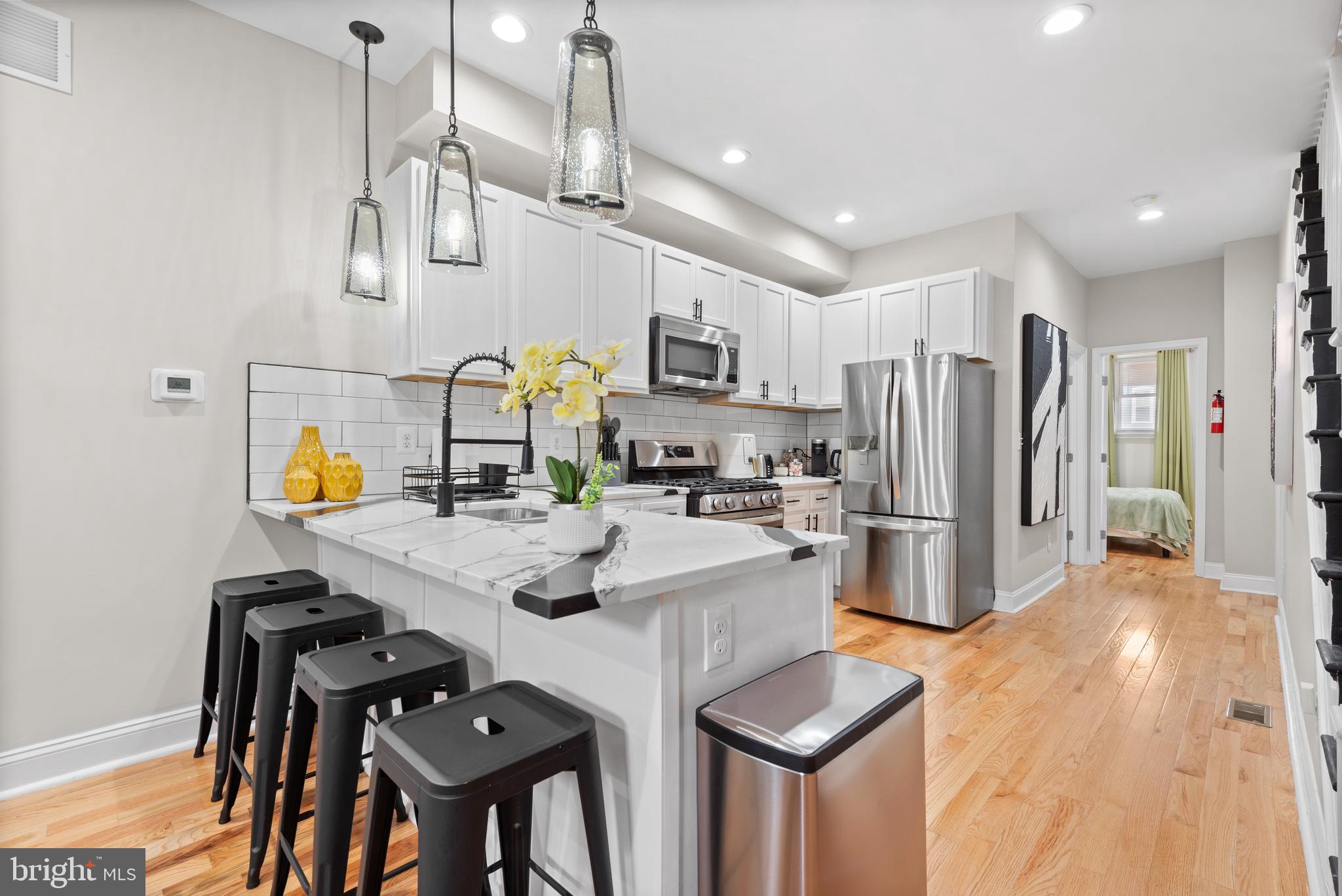 This stunning fully furnished four-bedroom, four-bath home blends contemporary with functional design and unbeatable city convenience. Step inside to discover an inviting open-concept main level featuring sun-filled living and dining areas that flow seamlessly into a gourmet kitchen designed for the modern chef. Enjoy sleek quartz countertops, premium cabinetry, top-of-the-line stainless steel appliances, and a spacious center island perfect for entertaining or casual dining. A versatile main-level bedroom with a full bath offers endless possibilities ideal as a guest suite, home office, fitness space, or creative studio. Upstairs, each bedroom boasts its own ensuite bath, providing both privacy and comfort. A full-size laundry on the bedroom level ensures everyday convenience. The fully finished lower level expands the home’s functionality even further, complete with its own kitchen, full bath, and laundry, perfect for roommates, in-law suite, or guest quarters or office.  The home’s prime location is nestled near Johns Hopkins Hospital and surrounded by ongoing neighborhood revitalization. You’ll find Starbucks, Eager Park, and a growing selection of cafes, restaurants, and community green spaces just a short walk away. The Inner Harbor, Fells Point, and downtown attractions are all minutes from your doorstep, offering the best of urban living.