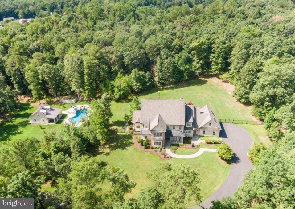 Welcome to this expansive estate boasting the largest lot in coveted Fawn Lake, spanning over 15 acres of picturesque landscape, fully fenced for ultimate privacy and security. A grand 2-story front entry welcomes you with a sweeping curved staircase. Entertain with ease in the expansive formal dining room, complemented by a large custom butler's pantry perfect for hosting gatherings. A well-appointed study with an attached bath offers versatility for remote work or relaxation.  Past the front entryway you'll find a light-filled 2-story family room. With its vaulted ceiling and stunning stone fireplace, this space offers a grand yet inviting atmosphere for gatherings and relaxation. Indulge your culinary desires in the gourmet kitchen, complete with a Wolf stove and SubZero fridge. The large eating area, featuring another charming stone fireplace, provides a cozy ambiance for family meals and entertaining, while a wall of windows floods the space with natural light, creating a bright and airy environment. Step into the main level primary suite, complete with a spacious walk-in closet and a private ensuite for your utmost comfort and relaxation. Convenience meets functionality with a second entrance featuring a mudroom, laundry area, and back stairs for seamless access. Upstairs, discover six generously sized bedrooms, including a bonus room equipped with sleep pods for added versatility and comfort. Notable enhancements include the addition of a new bedroom on the second floor, new carpet in the bedrooms, a new wine fridge in the butler’s pantry, and new HVAC unit (2020) for year-round comfort. The kitchen has been tastefully updated with white paint, offering a fresh and timeless aesthetic. The expansive basement of this remarkable estate, offers a haven of comfort and entertainment. Discover a sprawling bedroom suite complete with a walk-in closet and an upgraded bath, providing a serene retreat for guests or family members. Adjacent to the bedroom suite, is another versatile space perfect for an office or library, ideal for work or relaxation. Entertain in style in the expansive recreation room, offering endless possibilities for gatherings and leisure activities. Stay active and healthy in the home gym, equipped with all necessary equipment conveying with the property, ensuring your fitness needs are met right at home. Ample storage space is available in the huge storage room, providing organization and convenience. Experience unparalleled comfort with the upgraded geothermal heating/cooling system, offering energy-efficient climate control throughout the home. Escape to your private oasis outdoors, featuring an Anthony Sylvan saltwater custom pool with an upgraded pool house, complete with a chandelier, new flooring, special lighting, fan, Wi-Fi connectivity, and built-ins.  The rear of the home features a slate patio adorned with a wood-burning outside fireplace, creating the perfect ambiance for al fresco gatherings and cozy evenings. Enjoy premium amenities including two 1500-gallon propane tanks, a surround sound system throughout the porch, backyard patio, and main floor of the house, as well as an irrigation system for effortless lawn maintenance. Take advantage of the ASSUMABLE  LOAN at a remarkable 2.85% interest rate, offering exceptional financial flexibility. Enjoy resort-style living within the prestigious gated community of Fawn Lake where fine dining meets convenience with community restaurants just steps away from your front door. The private lake is perfect for motorcraft activities such as skiing, stand-up paddleboarding, tubing, and fishing. Enjoy endless days of fun and relaxation on the water, creating cherished memories with family and friends. In addition to the waterfront activities, residents of Fawn Lake enjoy access to world-class recreational facilities, including tennis and pickleball courts, providing opportunities for friendly competition and fitness. Welcome home!