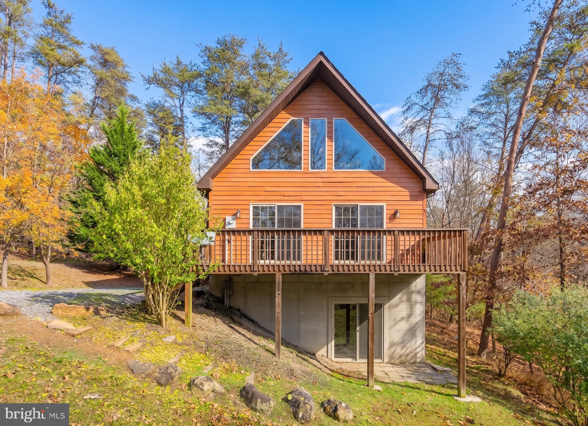 Spacious, fully furnished woodland retreat just outside Berkeley Springs, offering room for family, friends, and guests to gather in a peaceful private setting. This well-appointed cabin features 5 bedrooms plus an open loft sleeping area, 3 full bathrooms, and a flexible layout ideal for a vacation home, full-time residence, or investment property. Recent improvements include new hardwood flooring on the main level and upper-level primary bedroom, a new range, commercial-grade washer and dryer, and three large-screen TVs purchased in 2025. The inviting interior offers comfortable gathering spaces, a spacious kitchen, and a partially unfinished basement providing valuable storage and laundry space. Outside, enjoy a wooded setting with a private creek, nature trail, fire pit, hammock, deck, and electric smoker for easy outdoor living and entertaining. Located just 4 miles from Cacapon State Park and a short drive to downtown Berkeley Springs, Winchester, hiking, fishing, restaurants, shopping, and other local attractions. The property conveys fully furnished for a convenient turnkey transition, and the community allows short-term rental usage. See seller docs for utility details, improvement summary, and additional information on rental potential.