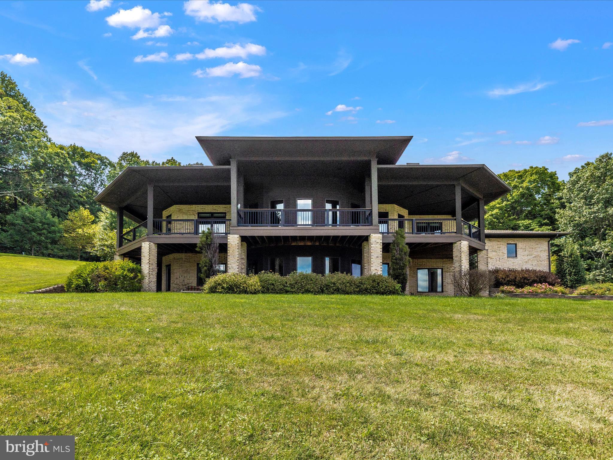 This stunning custom-built luxury mountain home on 12+ acres is truly a rare find! A brick fortress perched on top of the hill, this home remains cozy and ready for family and friends. Meticulously planned, prepare to be captivated by the impeccable attention to detail and luxurious finishes throughout. The main entry patio with its lanai-style is ideal for long summer evenings of private forest views—a true outdoor living space. The locally-made custom entry door gives way to 12’ ceilings, wooden beams throughout, floor-to-ceiling stone fireplaces, custom cabinetry, hardwood flooring and hand-scribe shelving that offer the perfect blend of elegance and comfort. The open floor plan beckons you to step back outside to the front deck and take a deep breath, look out to the mountains and consider the possibilities of this bonus outdoor space while watching the seasons change before your eyes. A true cook's kitchen, generous living room and dining room share both of these views from the inside. The kitchen features include abundant counter space, luxury appliances, a jaw-dropping copper hood, hand-made stained glass door accents, several custom drawer organizers for all of your spices, cooking utensils, small appliances, oils and larger seasonings.  Any cook knows there's no such thing as too much kitchen and the adjacent oversized pantry and laundry room stores a secondary refrigerator, custom cabinetry with pull-out storage drawers, full pantry cabinets, laundry facilities, wall-mounted ironing board, storage cabinets and a utility sink. The office boasts beautiful views and easily accommodates two desks, accessed by a custom-made stained glass accent door from the foyer. An oversized 3 car garage with a utility sink offers main-level entry to the house and is conveniently located near a half bath. There are 4 generously sized suites, a private retreat for every member or guest of the house! You will find two suites on the main level, both with stunning views and wood ceiling beams. The primary suite is pure luxury with an oversized soaking tub, walk-in jetted shower built for two, and a large walk-in closet. The third and fourth suites, located on the lower level, are well-appointed with spacious bathrooms, custom cabinetry, granite counters, walk-in showers & beautiful views to boot!  A large walk-in closet or additional storage room is accessible from one suite downstairs. Ready to relax with the family & friends for movie night or the big game? Or maybe entertain? The family room features a cozy stone surround fireplace, custom cabinetry & built-in surround sound! The bar, located off the family room, is equipped with a refrigerator, dishwasher, warming drawer and additional television hook-up, perfect for catching the score on that other important game! The lower level steps out onto the covered patio with bricked patio for fresh air and captivating mountain views, perfect for entertaining. Terraced walls, professional landscaping with drip irrigation and lighting, and peaceful mountain views abound.  Additional features include geothermal HVAC w/ zoned heated floors, whole home humidifier and dehumidifier, Pella casement windows and exterior doors, built-in blinds and generac power system so you never need to worry about losing power. Looking for things to do?  You are minutes (sometimes steps) away from local award-winning wineries, orchards, hiking trails, historic Fort Richie and more! If it feels like you are away from everything, you are, but you are still minutes from all the necessities. Ten minutes from I-70 and also close to Rt 15 puts you in easy reach of Frederick, DC and Baltimore. This home is in a dream location for everything your heart desires. Don't miss out on the opportunity to make this stunning, unforgettable property your new home!