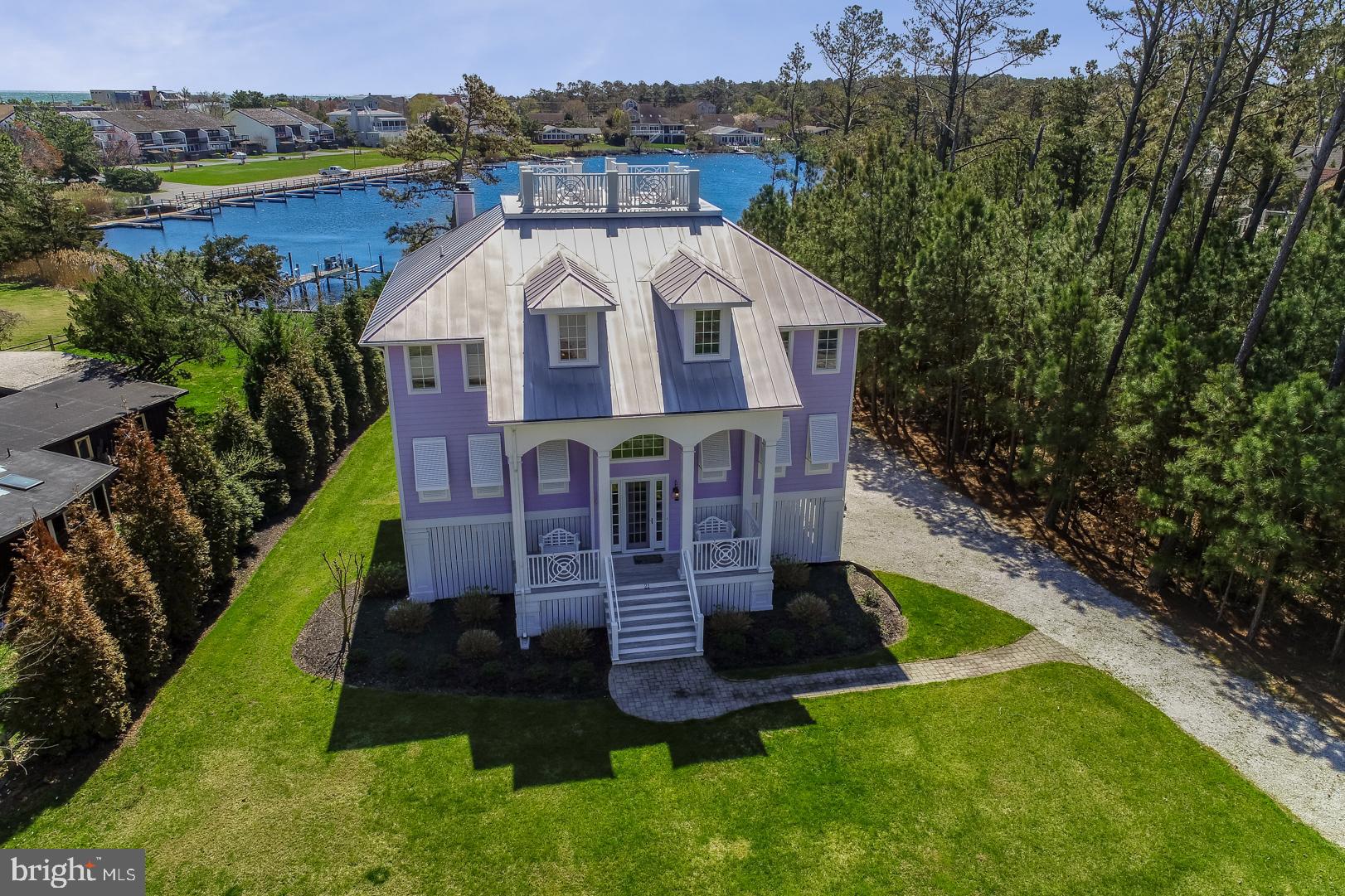 21 Holly Road is an exquisite waterfront home with stunning views of the North Shores marina basin and situated only steps from the private beach. The owners of this home spared no expense when designing this Key West style residence. The cheerful exterior, Bahama style hurricane shutters, pristine landscaping and spacious front porch create the most inviting exterior. Calming coastal colors, rich hardwood floors, crisp white wainscoting, and soaring ceilings greet you upon entry. The 2-story great room is flooded with natural light through the floor to ceiling windows and the sun reflecting off the water will be sure to captivate you. The ultra-functional and open floorplan features custom built-ins surrounding a beautiful gas fireplace in the great room and adjacent formal dining space, all overlooking the water. The gourmet kitchen features Carrara marble counters, tiled backsplash, Sub Zero refrigeration, Wolf gas cooktop, custom hood, wine fridge, island and cabinetry with pull out shelving offering ample storage. In addition, the main level offers a large laundry room, 2 guest bedrooms and 1.5 baths. The beautiful staircase leads you to the third level where you will find a loft area complete with a private office space and wet bar. In addition, this level includes a stunning master suite featuring a spa style bath and 2 additional guest bedrooms. Aside from the amazing interior, the outdoor and waterfront living spaces are truly spectacular. The relaxing front porch, multi-level covered, open and screened porches, and large rooftop deck span a total of 1865 square feet. The spacious rear yard has plenty of room for a pool and there is potential for a private boat dock for direct access to the marina basin, which leads to the Lewes Rehoboth Canal. Additional features include an elevator, outdoor shower, storage for beach toys and much more. This property truly has a lot to offer in the highly desired and private beach community of North Shores.