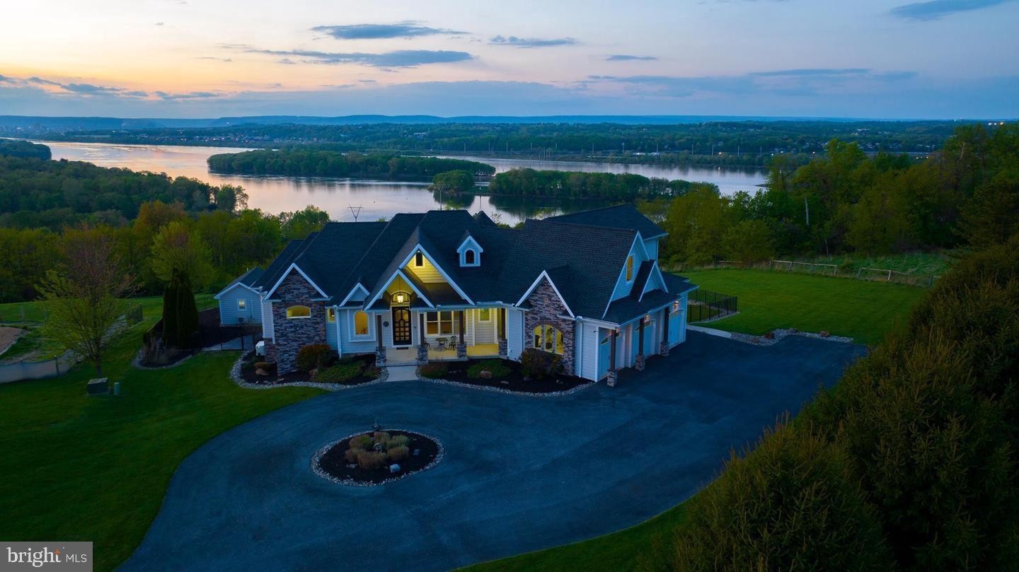 Wow what a view from this approx 5,000 + sq ft Home situated on 3 acres overlooking the river and Harrisburg! Custom built home comes fully furnished and featuring an inground swimming pool with a pool house, hot tub, outdoor stage area, pickle ball court, and more! Feel like you are on vacation all year round! This beautiful home offers a bright and open layout with modern, luxurious - custom fixtures throughout. The gourmet kitchen offers high-end appliances and countertops. A breakfast area offers panoramic views. The kitchen opens to a family room with exposed wooden beams. First floor master suite includes a luxurious ensuite with a jacuzzi tub in the center, dual vanities, and a tiled walk-in shower with multiple rainfall shower heads. Enjoy the wonderful views in every room on the main level. The lower level offers a unique one-of-a-kind entertainment experience. Featuring an open area for entertaining/gathering, a center stage, A guest bedroom with private bath is also located on this level. The upper level offers a rec room, two additional bedrooms, and full bath. Energy efficient home with solar panels and a back up generator, full laundry room. This home offers a total of 4 bedrooms, 3 full baths, and 2 half baths. This is truly a once and a lifetime opportunity to own this custom home designed for indoor and outdoor entertaining with one-of- a kind views.