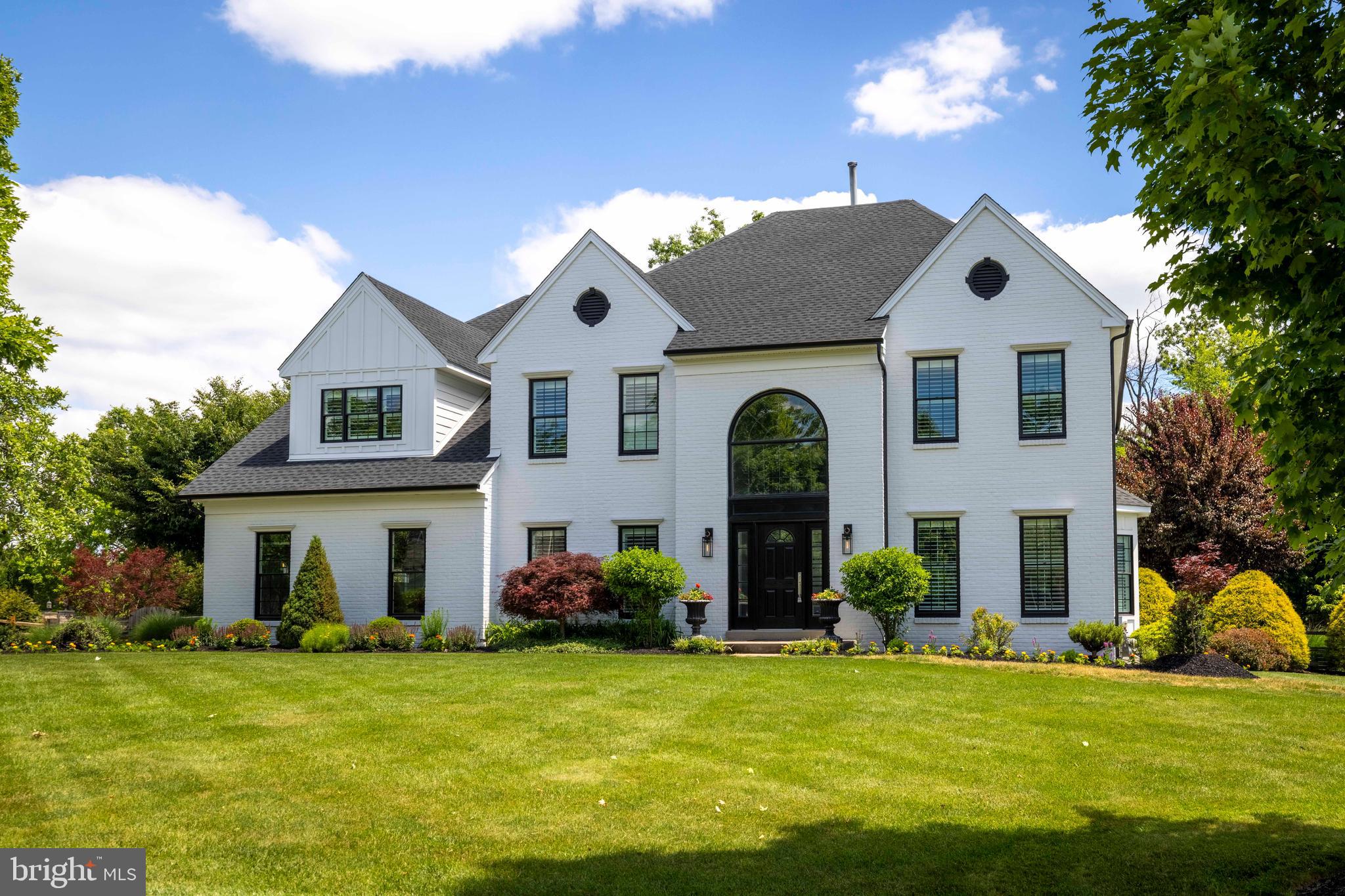Set on a generously sized lot with meticulously maintained landscaping and backing to serene woods, this home makes a striking first impression with its white brick and Hardie Board exterior accented by black matte details. The welcoming front entry opens to a front to back foyer featuring rich hardwood flooring, a beautiful staircase, and a double coat closet. Hardwood floors extend throughout most of the main level, adding warmth and continuity. Throughout the home, an eye for detail is evident, decorated beautifully with custom window treatments that perfectly complement each room. Just off the foyer, the formal living room, currently used as a home office, features French doors with custom crown and dentil molding. Across the foyer, the formal dining room is enhanced by grasscloth wallpaper, custom wainscoting, and crown molding, creating an ideal setting for gatherings and special occasions. The kitchen connects to the dining room through a butler’s pantry with glass cabinetry, quartz countertops, and a tile backsplash. A true chef's dream, the kitchen features a layout designed for effortless meal preparation and high-end entertaining. Premium finishes include quartz countertops, a marble subway tile backsplash, pull out pantry shelving, a Viking double wall oven, five burner cooktop and refrigerator, a built in Sub Zero wine refrigerator, wine storage, a coffee station, and a center island with seating for four. The breakfast room offers sliding glass doors to the outdoor living area. The great room features soaring twelve foot ceilings, a floor to ceiling stone wood burning fireplace, and windows that fill the space with natural light. The main level also includes a private office with a bay window and plantation shutters, and a well-appointed powder room. Located off the oversized three car attached garage, the laundry and mud room includes tile flooring, a granite folding station, tile backsplash, utility sink, abundant cabinetry, and custom built in storage. The second floor offers four generously sized bedrooms with hardwood flooring throughout, and all bathrooms have been tastefully updated. The primary suite features vaulted ceilings, plantation shutters, a sitting area, a double closet, and two walk in closets. The spa inspired ensuite bath showcases radiant heated tile flooring, quartz countertops at the dual vanity, custom flush mounted mirrors, a soaking tub, and a spacious stall shower with tile surround, built in bench, and private water closet. The princess suite includes a walk in closet and a private ensuite bath, the third bedroom enjoys access to a full hall bath, and the fourth bedroom offers a double closet and peaceful backyard views. The finished basement significantly expands the living space with plush carpeting, recessed lighting, and includes a gym and storage areas. Outdoor living is truly exceptional. Surrounded by mature landscaping and wooded views, the backyard offers a private retreat designed for relaxation and entertaining. An expansive stamped concrete patio provides space for dining and lounging. The custom grilling station is complemented by a beautiful stone island with a marble top and high top seating for five. A covered patio with a ceiling fan, television, and lighting creates a comfortable gathering space, and a stone wood burning fireplace adds warmth during cooler months. The centerpiece of the resort style yard is the sparkling heated swimming pool enhanced by an integrated hot tub and a cascading waterfall. The entire backyard is fully fenced and showcases the same meticulous care found throughout the property. Numerous recent improvements provide peace of mind, including a new roof, Hardie Board siding, and new top of the line windows and a patio door, all installed in 2024, and a new hot water heater installed in 2025. This home combines timeless design, extensive updates, outstanding indoor/outdoor living spaces, and an unbeatable location to create a rare offering.