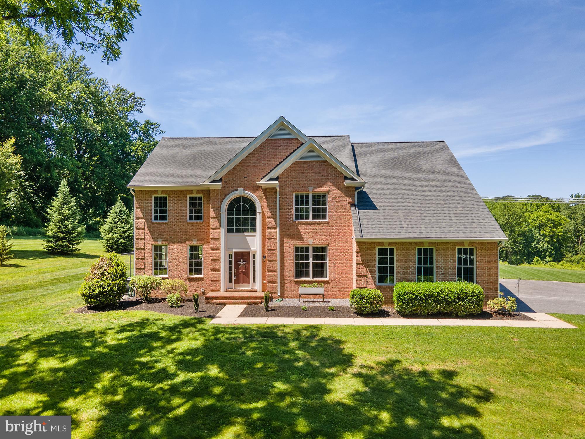 1650 Village Green Dr is an exceptional property with all of the privacy, space, amenities, acreage, and indoor and outdoor living luxury you could want in desirable Woodbine spanning 4.5 acres. A true rural estate, this property is perfect for homesteaders or those that want a rural life with true off-grid living but convenient to all commuter routes and amenities. With over 5,000SF of living space, this stately brick colonial has it all. A soaring foyer with dual staircases greets you. The living room, office, dining room, breakfast/morning room, expansive well appointed kitchen, and large family room comprise the first floor with hardwoods throughout, oversize windows, and amazing natural light. The attached 3 car garage features direct access to the family room/kitchen area with dual closets and an entryway landing. The fully equipped chef's kitchen features an expansive island with seating for everyone, granite countertops, gas cooking, glass front cabinetry, a pantry, coffee bar area, and stainless appliances. The large family room is open to the kitchen, features a propane fireplace, and the breakfast room is drenched in natural light with a walk-out to the back patio. 4 extremely sizeable bedrooms and 3 full baths are upstairs with a wraparound hallway open to the foyer below. The phenomenal primary suite contains a tray ceiling, lots of large windows, an office or sitting room space, and a large walk-in closet. The stunning en-suite full bath was recently redone with custom dual vanity cabinetry, an amazing walk-in shower with beautiful tilework, seamless glass doors, luxury finishes, and windows. A built-in soaking tub with floor to ceiling tilework and water closet round out the spa-like experience this primary bath is sure to deliver. The other 3 bedrooms are large, bright, and one has its own private en-suite bath, with another full bath containing laundry finishing out the first floor. Each of the secondary full baths upstairs has a tub/shower combo and neutral tiling and fixtures.  Another recently installed custom full bath in the basement features a fully tiled walk-in shower. With 3 additional finished rooms, plenty of storage, and another laundry area, the basement only adds functionality and lots of floorplan flexibility and options. If SPACE is a priority, this is the home for you! Outside, the recently installed, jaw-dropping custom pool includes a sun-deck, lots of patio space, waterfalls, and a changing area. The 4.5 acres is almost completely private and has several chicken coops, lovely views, lots of yard space, and room for goats, pigs, or other larger livestock. This property is equipped with a fully installed, professionally commissioned solar photovoltaic and battery storage system. This is more than a generator; it is true self-power and off grid living capability. Details and documentation available with the listing. This property is the total package in so many ways. Privacy, space, indoor and outdoor amenities, an open floorplan, diligent maintenance, self-powered off grid living, all in a wonderful dead-end neighborhood in desirable Woodbine.