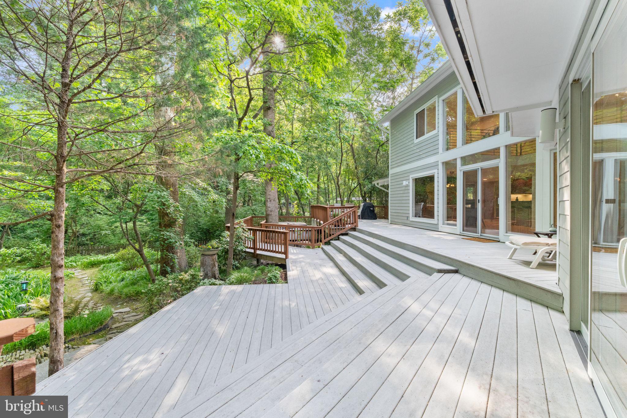 A Hidden Contemporary Retreat Inside the Beltway…

Tucked away on 1.34 private acres in the heart of Annandale, this extraordinary contemporary residence offers a rare combination of architectural design, natural beauty, and complete seclusion just moments from Washington, D.C., Reagan National Airport, and major commuter routes. Reached by a private 300-foot driveway off Little River Turnpike, the property unfolds as a peaceful sanctuary surrounded by mature trees, lush gardens, and the gentle sounds of Indian Run Creek.

Bathed in natural light, the home is defined by soaring ceilings, expansive walls of windows, and an open, flowing floor plan that blurs the line between indoor and outdoor living. Every principal room captures breathtaking views of the surrounding landscape, creating an ever-changing backdrop of greenery, birdsong, and tranquil water features. From sunrise through sunset, sunlight pours through the glass, illuminating the home's impressive architectural details and creating a warm, inviting atmosphere throughout.

Thoughtfully expanded and meticulously maintained, the residence offers five bedrooms, four- and one-half baths, and an exceptional collection of flexible living spaces designed to adapt to modern lifestyles. Elegant living and dining areas flow effortlessly into the family room, anchored by a striking double sided fireplace and oriented to embrace the spectacular natural setting beyond. A dramatic backlit granite feature wall creates a stunning focal point and adds a distinctive artistic element to the home.

The chef's kitchen is both sophisticated and functional, featuring custom Ferrari red European cabinetry, an oversized center island, premium countertops, double wall ovens, a microwave, and a five burner induction cooktop. Heated brushed Carrara marble floors add warmth and luxury, while dual glass front pantry closets, refrigerator drawers, and a professional prep sink create an ideal space for everyday living and entertaining alike.

The upper level is highlighted by an exceptional primary retreat designed for comfort and relaxation. A spacious loft provides additional flexibility as a library, lounge, or office, while the primary suite offers custom built ins, a fireplace, and expansive sliding glass doors opening to a covered veranda overlooking the serene grounds. The luxurious spa inspired suite includes separate his and her baths featuring custom European cabinetry, heated towel racks, oversized showers, steam features, and a Jacuzzi soaking tub perfectly positioned to enjoy peaceful views of the surrounding landscape.

A separate bedroom wing provides remarkable versatility with three additional bedrooms, a beautifully appointed bath with steam shower, generous built in storage, a bonus room ideal for work or wellness, and direct access to an upper veranda overlooking the gardens below.

Outside, the property becomes truly unforgettable. Designed as a private resort experience, the grounds feature expansive multi level decking, a hot tub nestled beneath the stars, and an extraordinary multi tier koi pond home to approximately fifteen vibrant mature koi. The soothing sound of cascading water flows throughout the landscape, creating a sense of calm and serenity rarely found so close to the city. Layered gardens, flowering plantings, towering trees, and the gentle presence of Indian Run Creek combine to create an environment that feels both magical and restorative.

The oversized garage offers extensive built in storage, EV charging capability, utility space, and the potential for a third parking bay conversion.

More than a home, this is a private estate offering an unparalleled lifestyle immersed in nature while remaining remarkably connected to everything the Washington metropolitan area has to offer. A truly rare opportunity to experience architectural elegance, sun filled living spaces, and resort inspired tranquility inside the Beltway.