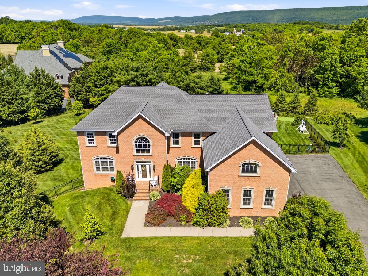 Welcome to Black Rock Estates, where luxury, space, and breathtaking views come together. Situated on a beautifully landscaped 0.69-acre lot, this impressive brick-front home offers over 4,800 finished square feet, 4 bedrooms, 4 full bathrooms, and a 3-car garage. Step inside to a grand two-story foyer with a sweeping staircase, hardwood floors, and an abundance of natural light. The gourmet kitchen features granite countertops, custom cabinetry, a center island, and an adjoining dining area that flows seamlessly into the stunning two-story family room. Floor-to-ceiling windows showcase scenic views while the gas fireplace creates a warm and inviting atmosphere. The spacious owner's suite is a true retreat, complete with a sitting area, fireplace, private balcony access, dual walk-in closets, and a spa-like bath with a soaking tub, oversized shower, and dual vanities. Generously sized secondary bedrooms and multiple living spaces provide room for everyone. Looking for even more potential? The approximately 2,000-square-foot unfinished basement offers endless possibilities to create the space you've always wanted, whether it's a home theater, gym, recreation room, guest suite, or all of the above. Outdoor living is just as impressive with a large deck featuring covered entertaining space and a hot tub overlooking the fenced backyard. Enjoy summer days by the pool and take in the panoramic mountain and countryside views.  Adjacent to the golf course and within minutes of commuter routes, shopping, dining, and everything Washington County has to offer, this exceptional property delivers the perfect combination of luxury, privacy, and convenience.