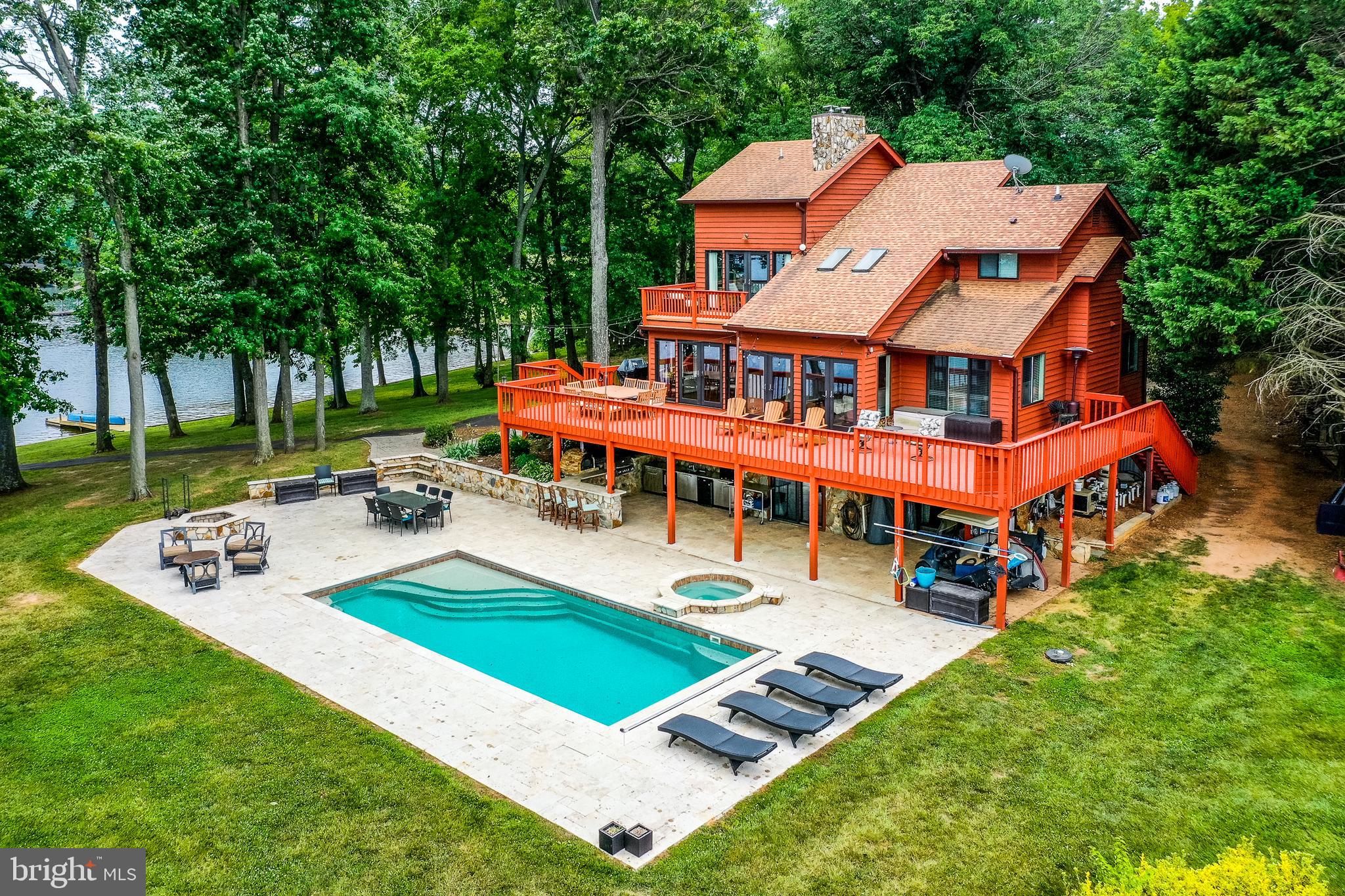 Paradise welcomes you at 96 Sandy Point Drive located on the coveted private side of Lake Anna. Your peaceful escape from reality awaits you in this beautiful waterfront retreat that offers resort style living with an in-ground pool that has an electric cover & hot tub with tavertine surround, outdoor kitchen with TV, ice maker, 2 refrigerators, gas & pellet grill & a wood fired pizza oven. Stroll on your very own premium point lot with over 600+ ft of shoreline, already protected by beautiful brand new bulkhead, alongside the clearest and deep water. Location is everything here, with sparkling Lake Anna as your focal point. Take a leisurely dip in the pool or unwind in the built in hot tub, all while taking in the gorgeous views. Large double-slip boathouse with two electric lifts, expansive sun deck and two storage rooms. You'll love entertaining here! This retreat offers over 3,600+ SQFT & features 6 BDRMS, 4 full BTHS (3 bedroom septic). Gorgeous Bamboo flooring, vaulted wood ceiling, custom barn door & 2 stone wood burning fireplaces showcase this retreat. The main level has a family room, dining room that is open to the kitchen, 2 bedrooms, a full bath, laundry room and a huge recreational/game room. The primary ensuite features vaulted wood & beam ceilings, walk-in closet, a private balcony overlooking the lake, double vanity, large walk-in shower and radiant heat flooring. There is also a second ensuite on the second level. Finished walkout basement has a family room, two bedrooms, full bath and 2 storage rooms. The large wrap around deck is perfect for summer BBQ's or for relaxing to take in the spectacular views and calming privacy. Sandy Point is a small gated community with only 8 homes and a community boat ramp. At this retreat you'll enjoy its incredibly convenient location; just a quick golf cart ride or walk to Elk Creek Country Store and gas station where you'll enjoy easy access to fuel for your boat, deli sandwiches, and more, and roughly 7 miles from New Bridge Landing Shopping Center, where you'll find groceries, restaurants, ABC, a nail salon, and more. Best of all, this home comes furnished and is turnkey! Yes, even the boat, jet skis, golf cart and the 86' pick-up truck convey! You will love it here! Schedule your tour today; this one will blow you away. SHORT TERM RENTALS ARE PERMITTED!