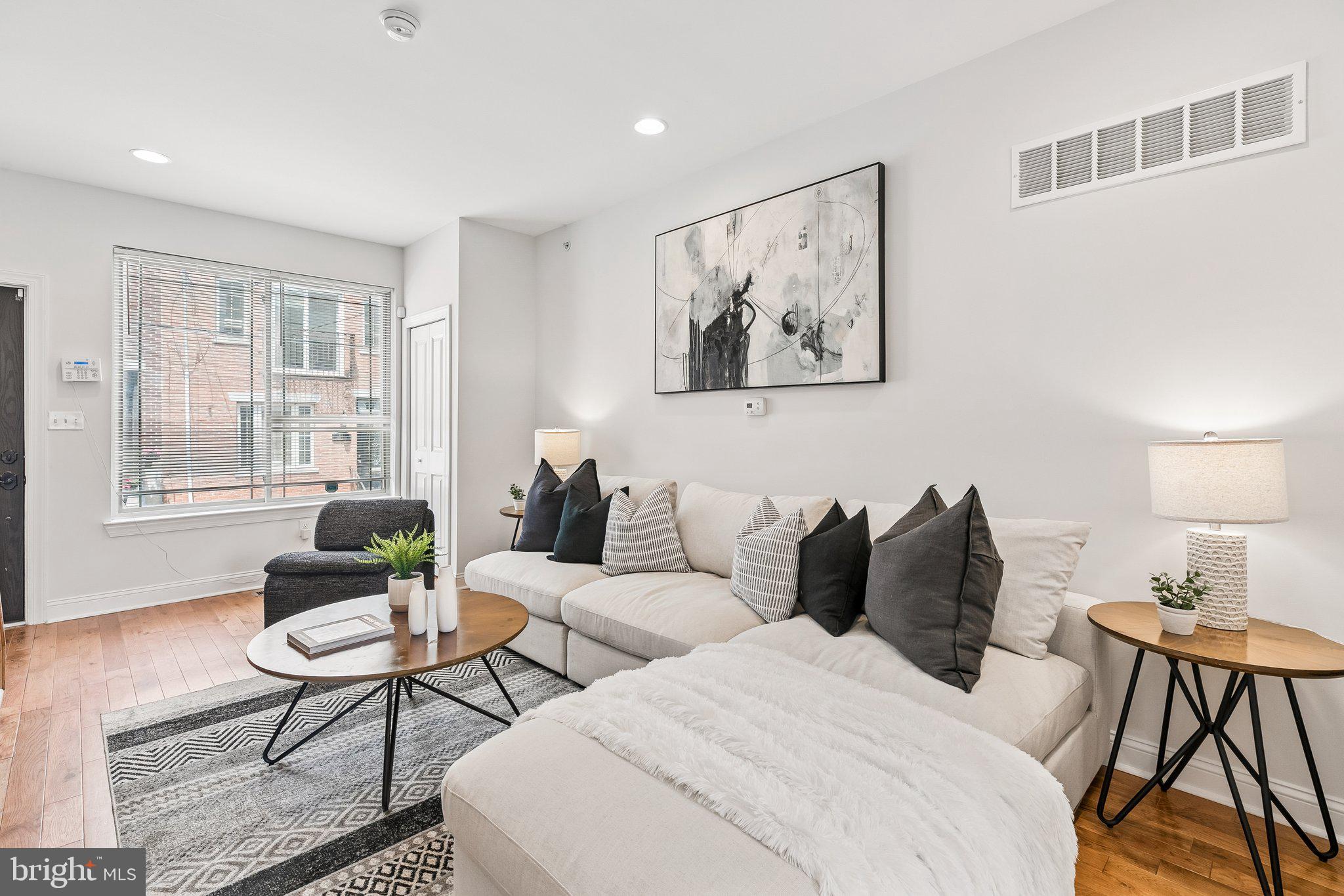 Nestled on a quiet, neighborly block in Point Breeze, this beautifully maintained 3-bedroom, 2.5-bath home offers a finished lower level, private roof deck, and an ideal layout for modern living. Step inside to a bright, open-concept main level featuring soaring ceilings, gleaming hardwood floors, and abundant natural light from the oversized front window. The spacious dining area comfortably seats 6–8 guests, making it perfect for entertaining and holiday gatherings. The updated kitchen boasts ample cabinetry, marble countertops, a stylish chevron tile backsplash, and a large island with additional storage and seating. A dramatic picture window above the sink overlooks the generous rear patio, an ideal space for grilling and outdoor dining. A convenient powder room and coat closet complete this level. The second floor features two bright and airy bedrooms, each offering generous closet space, large windows, hardwood floors, and high ceilings. A well-appointed hall bathroom includes a single vanity and jetted tub. Occupying the entire third floor, the expansive primary suite easily accommodates a king-sized bed, multiple dressers, and nightstands. The oversized walk-in closet provides exceptional storage, while the ensuite bath features a double vanity and walk-in shower. The private roof deck offers stunning skyline views and is the perfect place to unwind with a cocktail while enjoying the sunset. The finished lower level, complete with tall ceilings, provides flexible living space ideal for a family room, media room, playroom, home office, or gym. Conveniently located near neighborhood favorites including American Sardine Bar, Schmaltz, Chicks, Greenstreet Coffee, and Hannah K's, this home also offers easy access to Washington Avenue and everyday essentials at Aldi, CVS, Sprouts, and Target. Freshly painted and move-in ready, this home is ready to welcome its next owners!