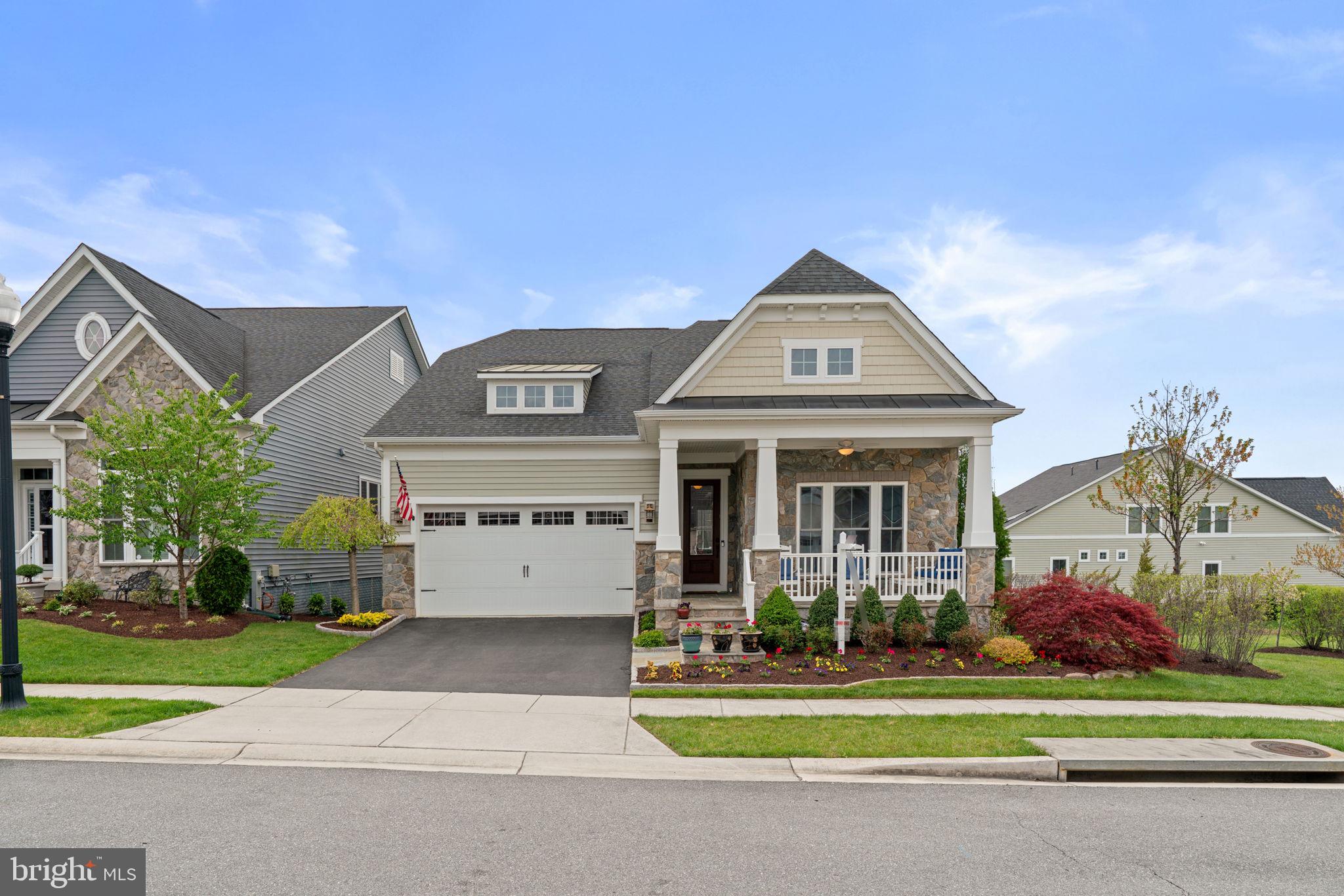 Excellent, stone-accented villa-style residence built by NV Homes in the sought-after, amenity-rich 55+ community of Bluffs at Two Rivers, featuring owned solar panels for enhanced efficiency. This vibrant community offers exceptional amenities, including a clubhouse and a fully equipped fitness center.  Lush, professionally designed landscaping enhanced by an irrigation system, Belgium block detailing, and vibrant plantings creates a stunning approach, leading to a spacious covered porch that welcomes you into a refined interior defined by elegant architectural details, a neutral designer palette, and thoughtfully curated finishes throughout. Hardwood floors span the main level, beginning in the foyer and extending down the hallway to a private study with French doors and custom built-in bookcases also ideal as an additional bedroom. A formal dining room is highlighted by lower wainscoting, a tray ceiling, and graceful curved architecture. A functional mudroom with built-ins and garage access, along with a well-equipped laundry room featuring a sink and upper cabinetry, adds everyday convenience. The open-concept great room is designed for both everyday living and elevated entertaining, featuring a gourmet eat-in kitchen with an oversized island illuminated by pendant lighting and featuring breakfast bar seating, stainless steel appliances including a beverage refrigerator, a pantry, and a subway tile backsplash with a herringbone accent. The sunlit breakfast area offers a charming corner built-in and exterior access, while the adjoining family room impresses with coffered ceilings and a cozy fireplace. Two additional bedrooms reside on the main level, including one with an attached full bathroom with dual entry access from the hallway, as well as the owner’s suite privately situated off the family room. This comfortable retreat offers a tray ceiling, and a sitting room extension with private access to the deck. The en-suite owner’s bath is appointed with dual vanities, a soaking tub, a separate shower, a private water closet, and a spacious walk-in closet. The walk-out lower level thoughtfully expands the home’s living space, featuring a spacious recreation room with a game area extension complete with a wet bar, striking backsplash, and under-cabinet lighting. A large open area offers ample room for both entertaining and relaxed lounging, complemented by a full bathroom and a fourth bedroom or versatile bonus room accessed through elegant French doors. Outdoor living is equally impressive, featuring a low-maintenance sundeck, a covered pebble patio below, and a beautifully landscaped backyard. The side yard offers additional outdoor space, a rare bonus for this style of home.