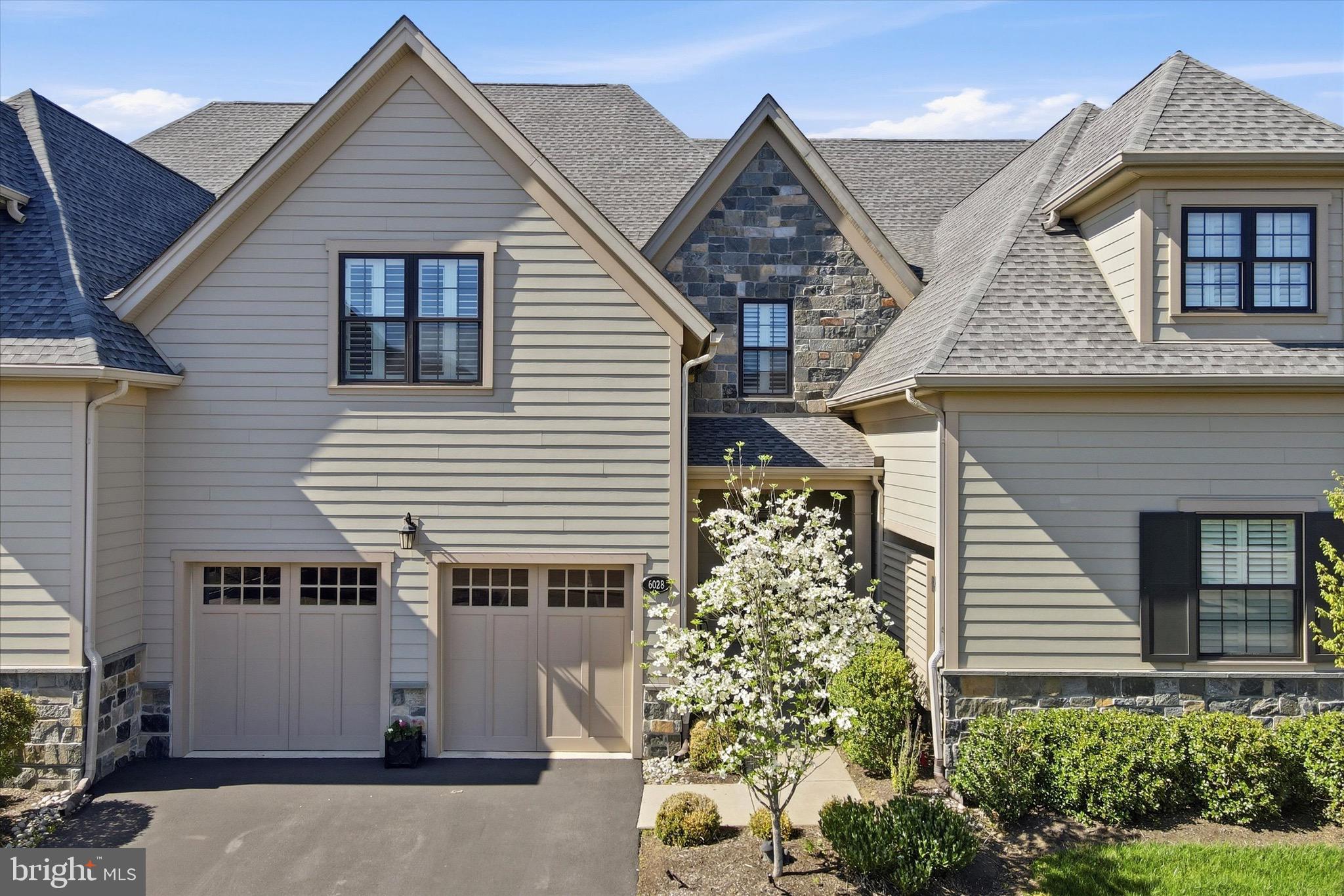 Welcome to 6028 Creekside Drive in the Reserve at Creekside - the area’s premier carriage home community This exceptional 3 bedroom, 2.5 bath Gowen model showcases a spacious open concept floor plan, thoughtfully designed with flexible living spaces and refined finishes, perfect for both everyday living and elegant entertaining. A welcoming foyer with coat closet, powder room, and access to the attached two-car garage leads to a large dining room with tray ceiling, classic columns and wainscoting. The expansive great room features a gas fireplace set within a striking marble accent wall and flows seamlessly into the chef-inspired kitchen with an oversized center island, quartz countertops, stainless steel appliances, custom tile backsplash, and walk-in pantry. A spacious composite deck extends the living space outdoors, ideal for relaxing or hosting guests. Upstairs, the luxurious primary suite offers two custom walk-in closets and a spa-like en suite bath with dual vanity, oversized glass-enclosed shower, and private water closet. Two additional generously sized bedrooms, a full hall bathroom, and a convenient second-floor laundry room complete this level. The full, unfinished basement with 9-foot ceilings provides endless possibilities for future living space, a home office, gym, or media room, and is already plumbed for a full bathroom. Notable upgrades include hardwood flooring throughout the main level, stairs, and second-floor hallway, custom cabinetry and millwork, recessed lighting, designer light fixtures, concealed sprinkler heads, and a whole-house water filtration and softening system. Residents of The Reserve at Creekside enjoy maintenance-free living along with exceptional community amenities, including a 4,500-square-foot clubhouse with gathering space, kitchen, fitness center, and an outdoor pool with a flagstone patio. Ideally situated in Whitemarsh Township, this home offers easy access to Fort Washington and Wissahickon Parks, as well as the shops and dining of Flourtown and Chestnut Hill, with convenient proximity to Routes 309, 476, and the Pennsylvania Turnpike.