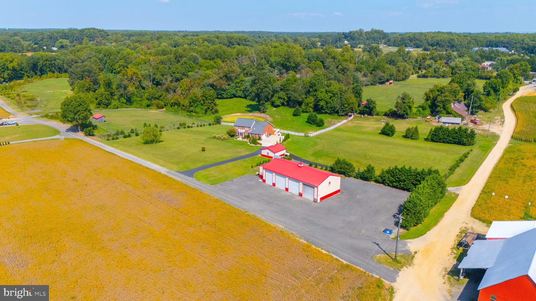 This exquisite custom-built all-brick home is situated on nearly 3 acres with stunning views of expansive farmland. The property boasts a wealth of features, including a 40'x80' 4-bay garage building with a pit, 20' ceilings, insulated doors, heating/air conditioning, an office with a loft, and a full bath. There is also an additional detached 2-car garage. The home offers an open floor plan with 9' ceilings, an upgraded kitchen featuring granite countertops, a gas stove, a wall oven, a microwave, and hardwood floors throughout. The bright and open family room and dining area provide a welcoming atmosphere. The primary bedroom is conveniently located on the main level and includes a luxurious bath with a tile shower and soaking tub, along with another guest bedroom and full bath. The upper level consists of 3 additional bedrooms and a full bath. The lower level is perfect for long-term guests, featuring a fully equipped kitchen, a great room, 2 bedrooms, a full bath, a sitting room, and more. The home also includes its own 2-car garage. 
This property is a must-see to truly appreciate all it has to offer. With quick access to Washington D.C., AFB, Annapolis, and the Naval Academy, it's perfectly situated for convenience and comfort.