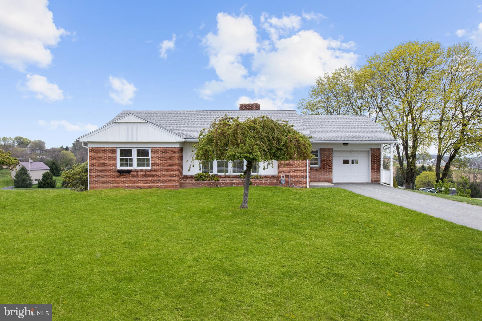 Welcome to this well-maintained solid brick rancher, nestled in a peaceful rural setting with scenic country views in both the front and back. Built and owned by the same family for the past 71 years, this home has been lovingly cared for and is now ready for its next chapter.
Step inside to find beautiful hardwood floors throughout the main level, a cozy living room with a wood-burning fireplace, and a large picture window that fills the space with natural light. The eat-in kitchen and formal dining area offer plenty of room for everyday living and entertaining.

Three spacious bedrooms and a full bath complete the main floor. The walk-out basement provides ample storage space and includes a second full bathroom—great for added flexibility or future finishing potential.

Enjoy your mornings or unwind in the evenings on the covered rear porch, the perfect spot to sip a cup of coffee while overlooking the peaceful fields behind the home.

Additional highlights include an attached garage in the front, a second attached garage in the rear, and generous outdoor space.

With timeless charm, solid construction, and so much potential, this home is a rare find. Schedule your tour today.