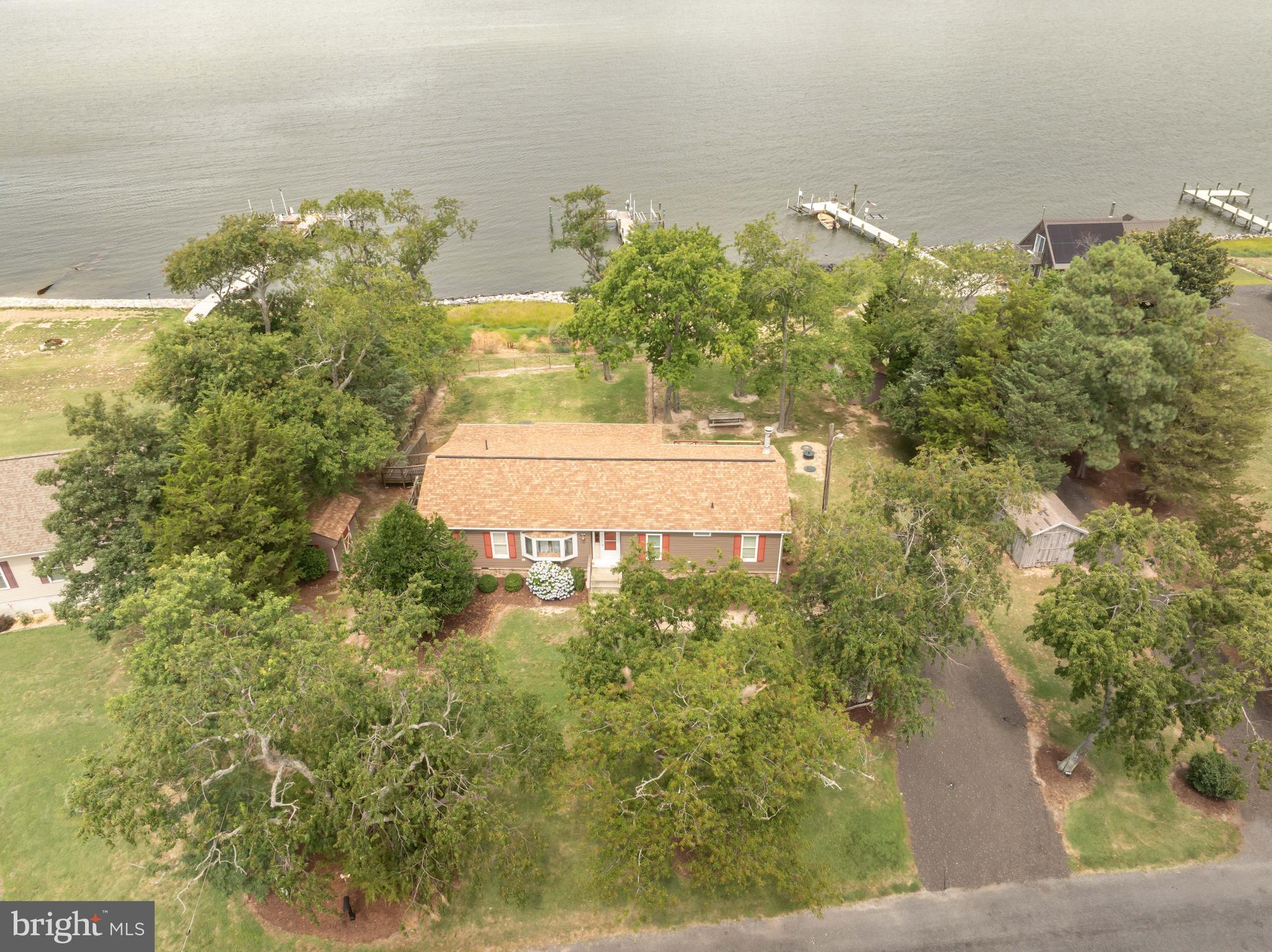 Welcome to 7940 Riverview. Located in the Waterside Village of Rumbley this beauty faces straight into the Tangier Sound/Chesapeake Bay!!! Pride of Ownership and attention to detail are evident both inside and out of this pristine property. This 3 Bedroom 2 Bath gem makes efficient use of every square inch of living space. The Primary Living Room is large enough for entertaining but isn't the only living space. Check out the Den which has Sliding Doors that face the Bay and has a propane fireplace for a cozy feel or to take the edge off on a cool day. Walkout from the family room to the spacious open deck or take cover in the screened in porch alongside. The Kitchen is ample enough to make meal prep a whiz and the breakfast nook is convenient for when the crowd is a little smaller. There is a dining area as well that can handle those larger get togethers. The Large Owners Suite is located on the opposite end of the home from the other two bedrooms giving all parties extra privacy! There are an ample mud room and a space currently used as an office if you have to bring work with you for your get away. The Fenced In area is great for pet detail and there is an Outdoor Shower to hose off after playing on the water. The Sturdy pier features a boat lift, cleaning station, electric supply and bench seating for your convenience. (P.S current owners catches Rockfish, Speckled Trout, and Red Drum right from his pier). The Rip Rap is well maintained, and the sea grasses help to prevent any washouts. There are three outbuildings for storage of all your work and play items as well. Owner would prefer to sell the home furnished so you can walk in drop the bags and enjoy. If you don't feel like cooking or want a night out... check out the Pit and Pub restaurant just down the street. When it comes time to launch or trailer your boat, the Rumbley Boat Dock is just around the corner.  This beauty truly needs to be seen to be appreciated... Book your Showing Today!!!