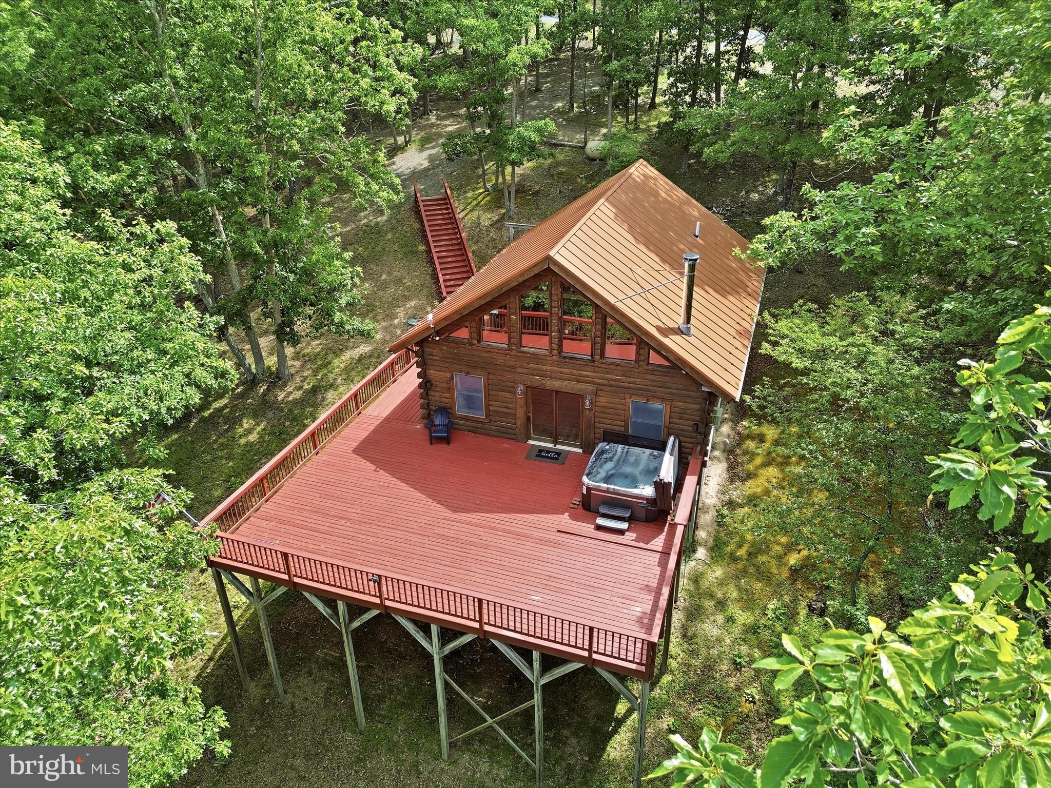 Escape to your own mountain retreat in the gated community of The Crossings at Great Cacapon. Nestled on 4.6 wooded acres, this authentic log cabin offers the perfect blend of privacy, rustic charm, and outdoor recreation.

Inside, you'll find an open-concept living area featuring vaulted ceilings, exposed beams, warm wood finishes, and a wood-burning stove installed approximately two years ago. The main level includes a kitchen with a breakfast bar that opens to the living area, a bedroom, full bath, and pantry. The loft overlooks the great room below and serves as a second bedroom complete with a half bath. The unfinished walkout basement offers abundant storage and excellent potential for future expansion, recreation space, or a workshop.

One of the highlights of the property is the 1,100+ square-foot deck, where you can enjoy the peaceful wooded setting, entertain guests, soak in the hot tub, or simply relax and take in the sights and sounds of nature. A firepit area off to the side of the home provides the perfect place to unwind on cool mountain evenings. Other highlights include the community amenities: access to the Cacapon River, a pavilion, and basketball courts. Recent updates include a metal roof approximately 5-6 years old and a Generac whole-house generator approximately 3 years old. The generator runs off of the 500-gallon propane tank, providing added peace of mind to its new owners.

Whether you're searching for a full-time residence or a weekend getaway, this mountain cabin offers the opportunity to enjoy the beauty and tranquility of Almost Heaven, West Virginia.