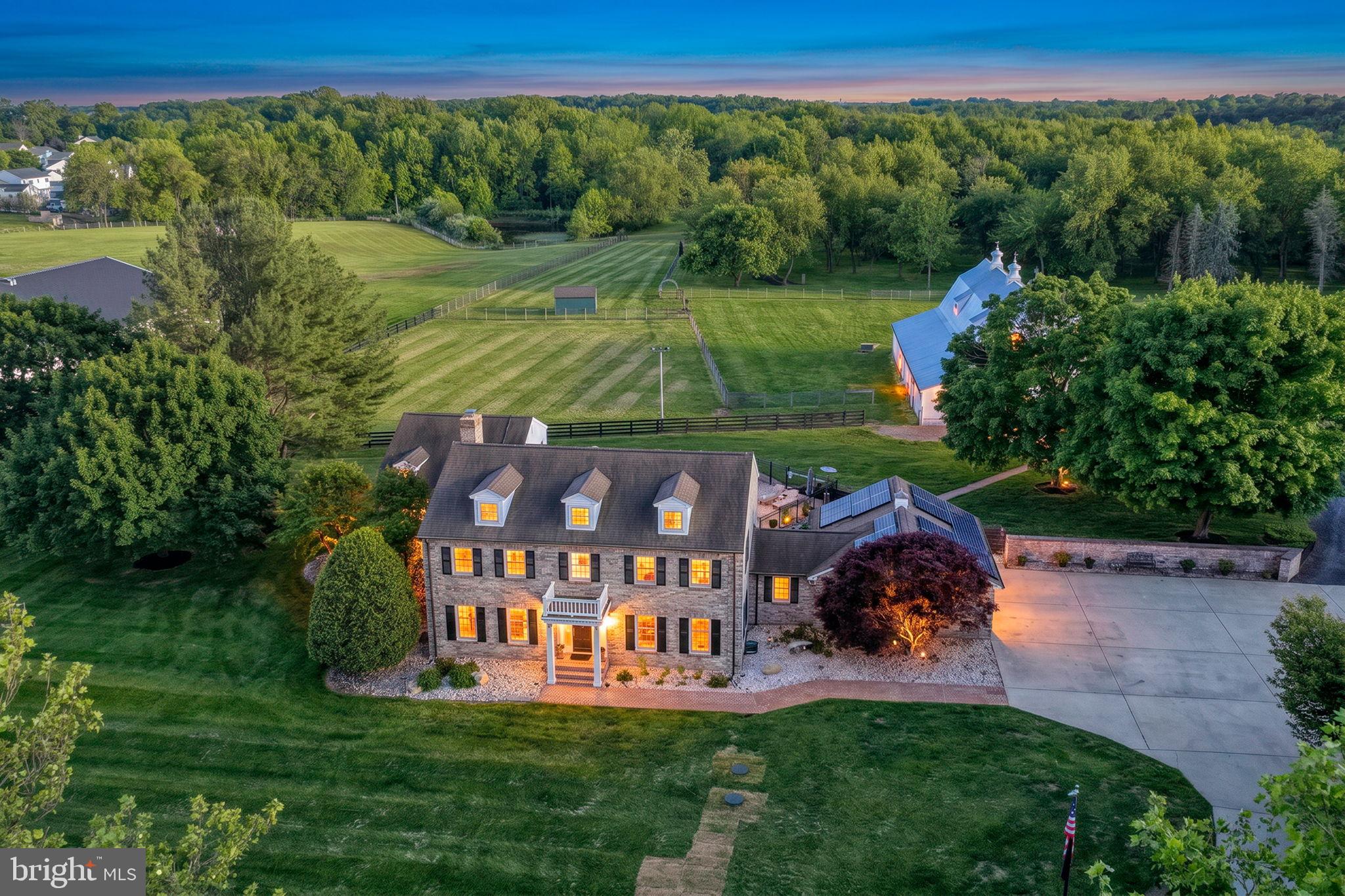 Beautiful Brick Colonial Estate set on 11 private acres backing to a State Wildlife Refuge, offering a rare combination of space, privacy, and versatility. With a thoughtfully designed layout and extensive outbuildings, the property is well-suited for a variety of lifestyles, from hobbyists and collectors to sufficient or outdoor-focused way of living. The home features 4 bedrooms and 4.5 bathrooms, along with multiple living areas, a formal dining room, and a private office. The kitchen is designed for both everyday use and, entertaining, with a large island, bar height seating, built-in ice maker, and a wine cooler. Outdoor amenities include a beautiful in-ground pool and expansive grounds that provide both open space and a scenic natural backdrop. The property offers an impressive 12 garage and storage spaces across multiple structures, with oversized doors and a separate large workshop building with six additional bays and separate living quarters above with 2-bedrooms, 2 bathrooms. A 2-car detached garage adds convenience near the home, while the layout allows for easy access and maneuverability for trailers or equipment. A well-appointed barn featuring 6 stalls, attached run-in, hay and feed storage, a tack room with washer/dryer and half bath provides additional flexibility for agricultural, recreational, or hobby uses. With ample room to expand, adapt, or simply enjoy the surrounding landscape, this property offers a unique opportunity to create a lifestyle tailored to your needs- all within minutes of shopping, dining, and major highways.