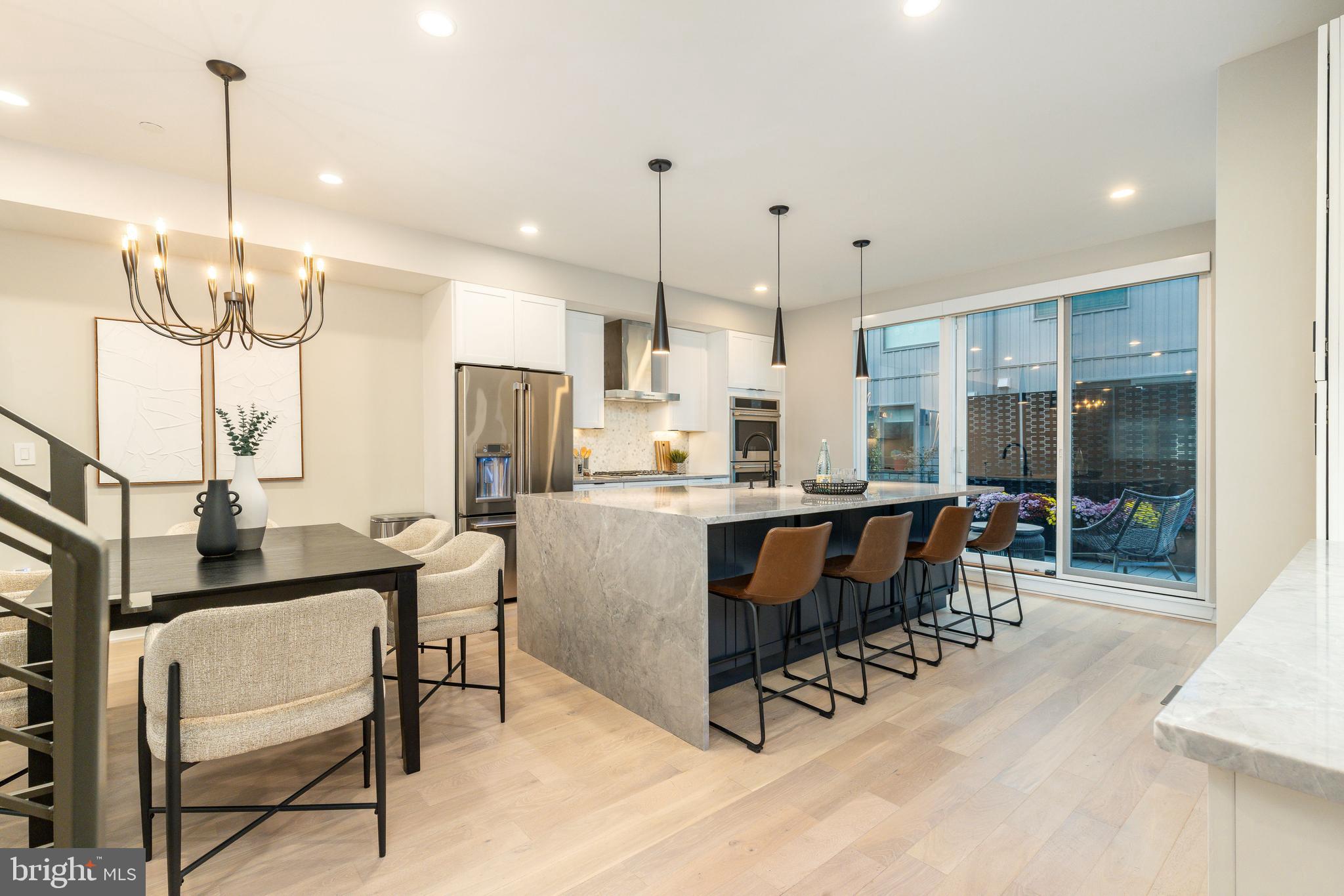 Luxury townhome with two car garage parking. This extra wide modern townhome at the former site of the Frankford Chocolate Factory present a unique urban experience in close proximity to Rittenhouse, major transportation routes, universities, and hospitals. Nearly 3,300 square feet of living space, custom designed finish selections, and fantastic skyline views. Go up the front steps into the expansive living room with 15+ high ceilings and an open floor plan concept that leads you into the dining and kitchen area. The oversized dining area features a convenient half bathroom and kitchen. The kitchen features an oversized center island, quartz countertops, tile backsplash, stainless steel Cafe appliances that include drawer microwave, cooktop, double oven, and range hood. Exit the back of the kitchen to the rear deck that extends 8 feet off the rear wall: perfect for entertaining guests, outdoor grilling, and dining under the stars! Upstairs you will find two large bedrooms with large closets and a shared full bathroom. This floor is also equipped with a laundry room with cabinets for storage. Continue to the top floor and enter the primary bedroom suite with an oversized walk-in closet. The primary bathroom features a freestanding soaking tub, oversized shower room of seamless glass, a private lavatory, a double vanity and radiant heated floors. Before you exit to the roof deck, there is a wet bar and sink conveniently located to entertain your guests as well as a half bathroom. The roof deck is complete with green and features spectacular panoramic views of the Philadelphia skyline. Special attention has been given to the rooftop design to maximize the usable space while enjoying the benefits of having a green roof. There is additional living space in the finished basement, perfect as an office, workout/fitness room, or additional sitting area. If those features aren't enough, pull into the private driveway of this development and into your two car garage. These homes have a Ring camera system and have dual-zoned energy-efficient HVAC systems with NEST thermostats. Metal handrails, recessed lighting throughout, and PELLA windows. Conveniently located near ALDI, CVS, Target, Sprouts Market, Whole Foods and Pet Smart. 8  Years remaining on the Tax Abatement.