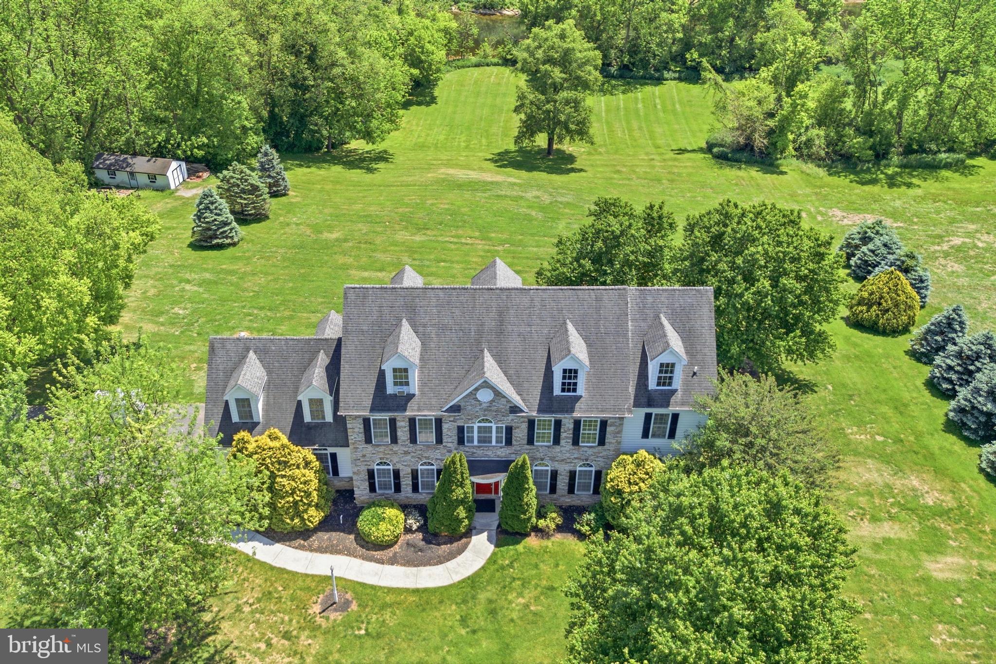 Opportunity knocks with this one-of-a-kind estate property set on 3.5 scenic acres overlooking the Conestoga River. This expansive Lancaster home offers a rare blend of space, flexibility, and peaceful waterfront living—ideal for multi-generational living, extended stays, or simply enjoying room to spread out.
Flexible floor plan allows for up to 8 bedrooms and 7 full bathrooms (1 bedroom on the main level, 4 bedrooms on the second floor, and 3 additional rooms on the third floor that can be used as bedrooms/offices). The main level includes a private in-law suite complete with its own bedroom, full bath, and living room with fireplace—perfect for guests or extended family. At the heart of the home, the kitchen with breakfast area flows seamlessly into the family room with fireplace and provides direct access to the expansive rear deck overlooking the river, creating an ideal setup for both everyday living and entertaining. A formal dining room with hardwood floors and a separate living room complete the main level. Upstairs, the second floor features four bedrooms, each with its own en-suite bath, including a spacious primary suite with a large bonus room or private office. The third floor offers additional flexible living space, including three bedrooms/offices, a full bath, and a generous common area—perfect for a game room, lounge, or movie area. The partially finished walkout lower level features extra-high ceilings and provides even more space for recreation, storage, or future customization. Recent updates include fresh paint throughout and new carpeting, while large windows capture the home’s stunning natural surroundings and river views. Step outside and enjoy the tranquility of the setting, with ample space to relax, entertain, and take in the beauty of the Conestoga River.  A truly rare opportunity to own a property that combines size, setting, and exceptional flexibility in Lancaster County.